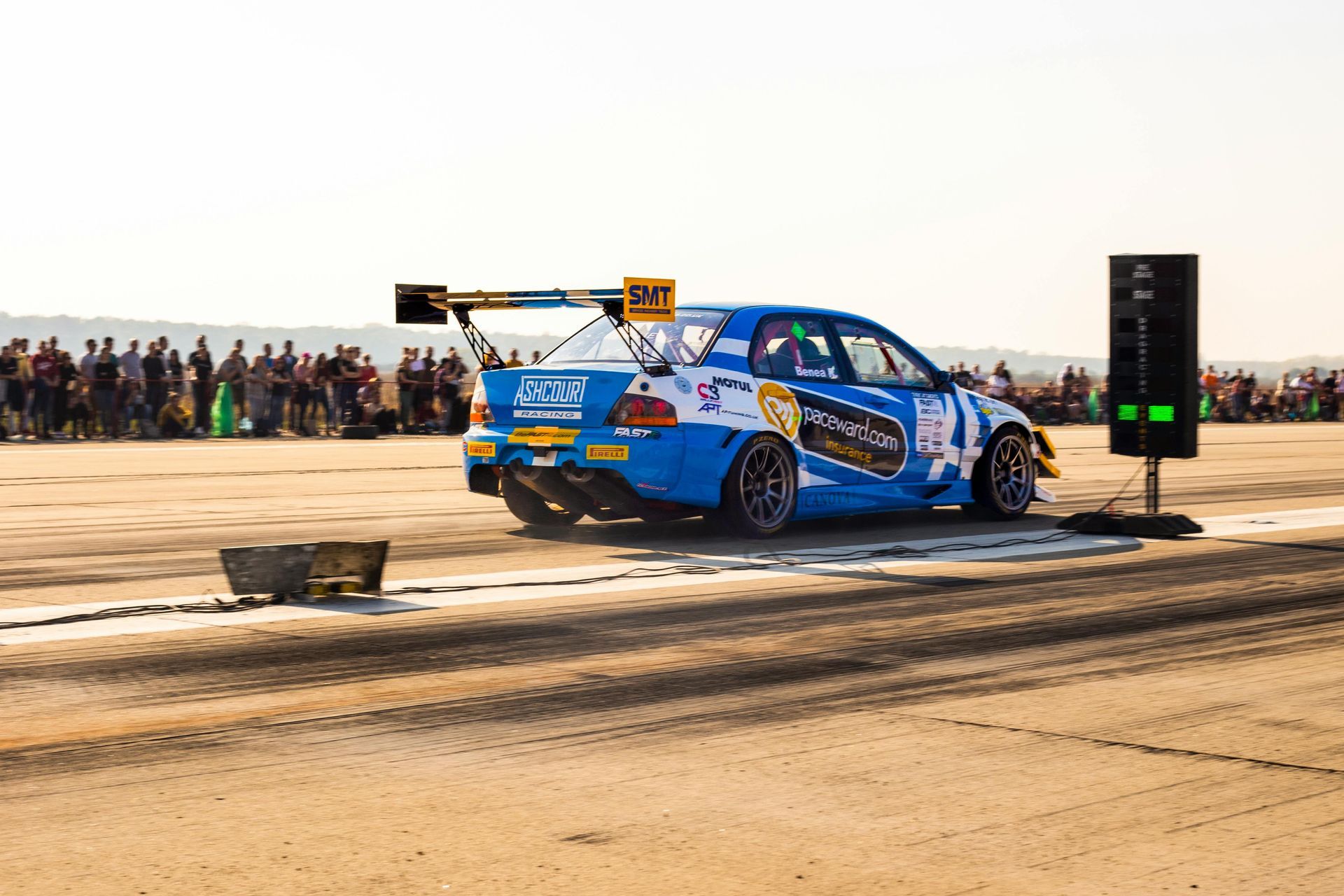 A blue and white race car is driving down a dirt road.