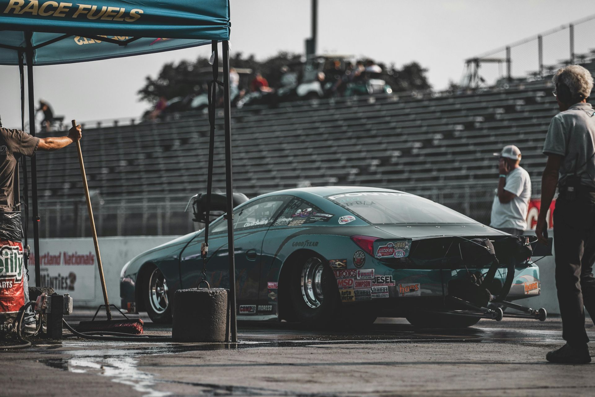 A man is standing next to a race car on a race track.