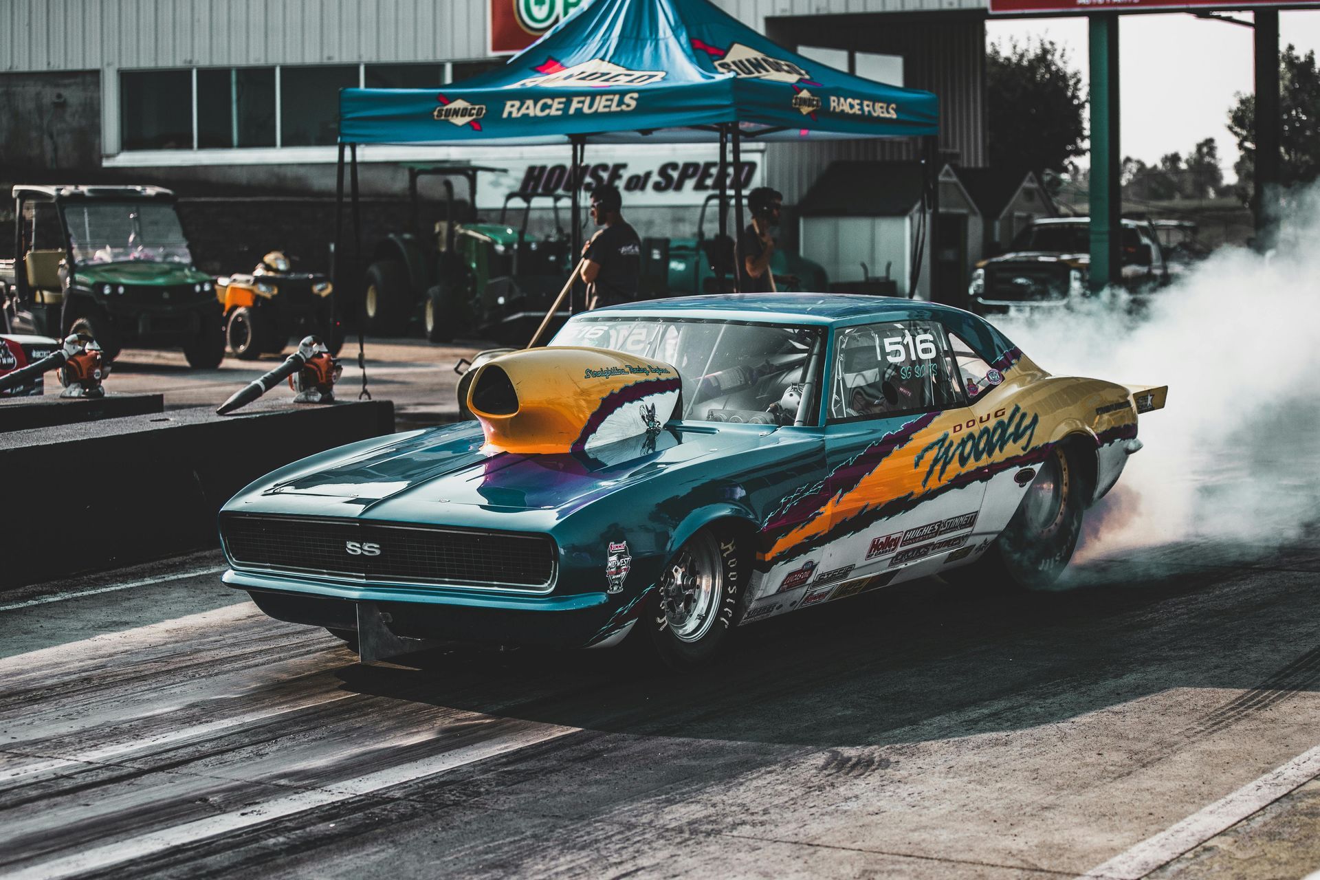 A blue and yellow race car is doing a burnout on a race track.