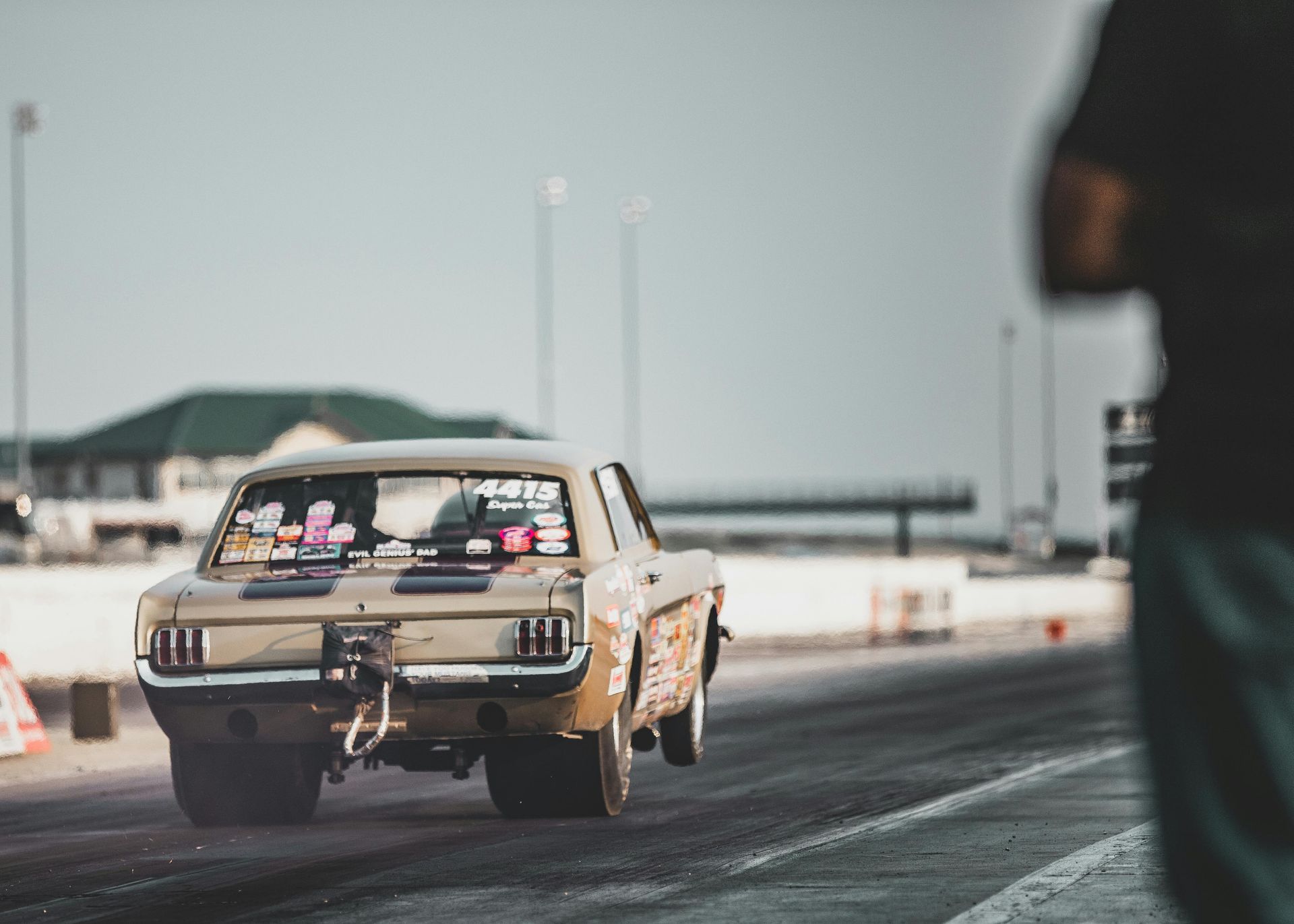 A car is driving down a race track and a man is standing behind it.