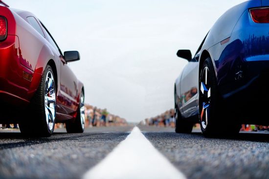Two sports cars are parked next to each other on a road.