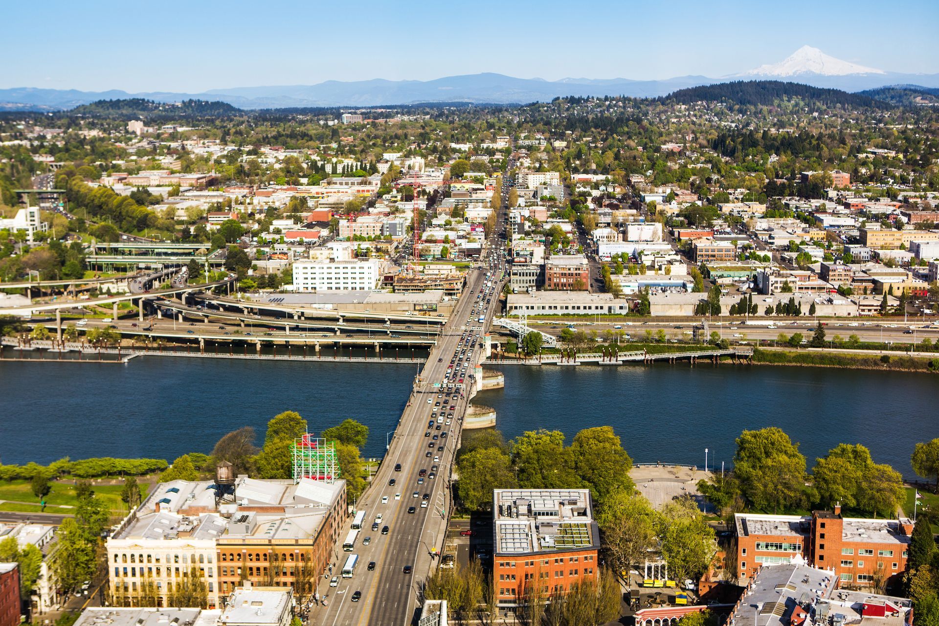portland photo showing a bridge over a river with mountains and city in the background
