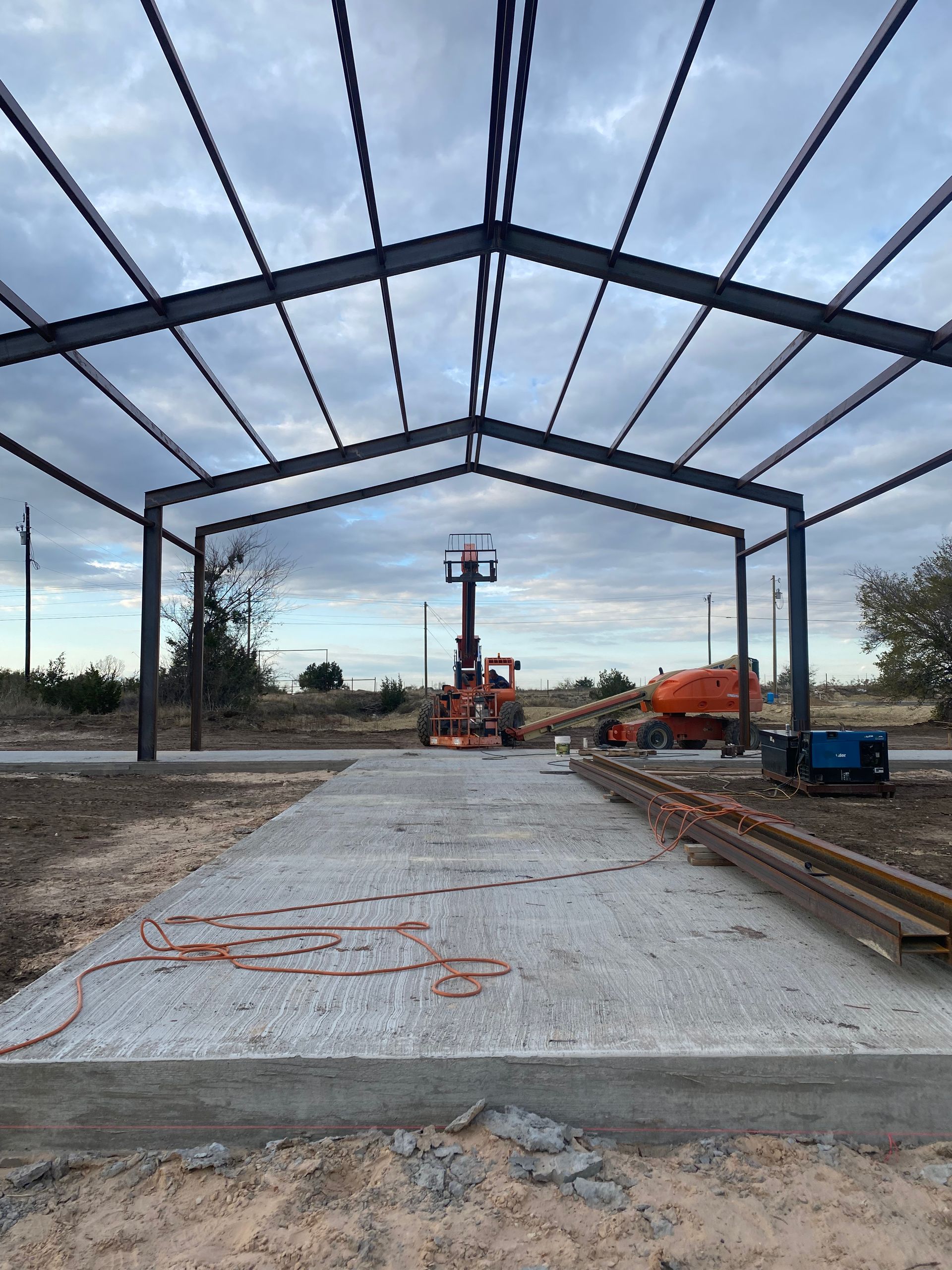 A large metal structure is being built in the middle of a dirt field.