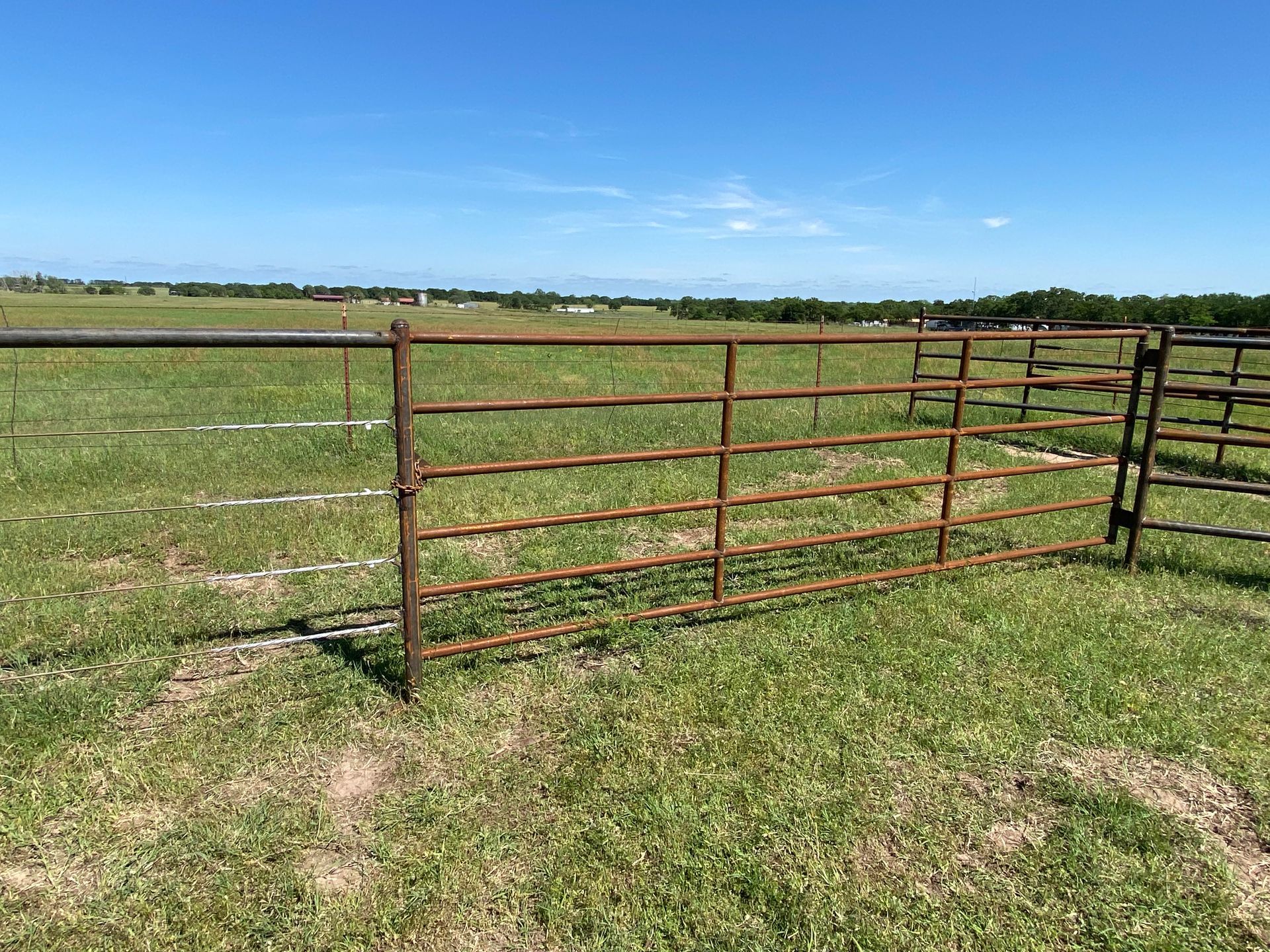 A metal gate is sitting in the middle of a grassy field.