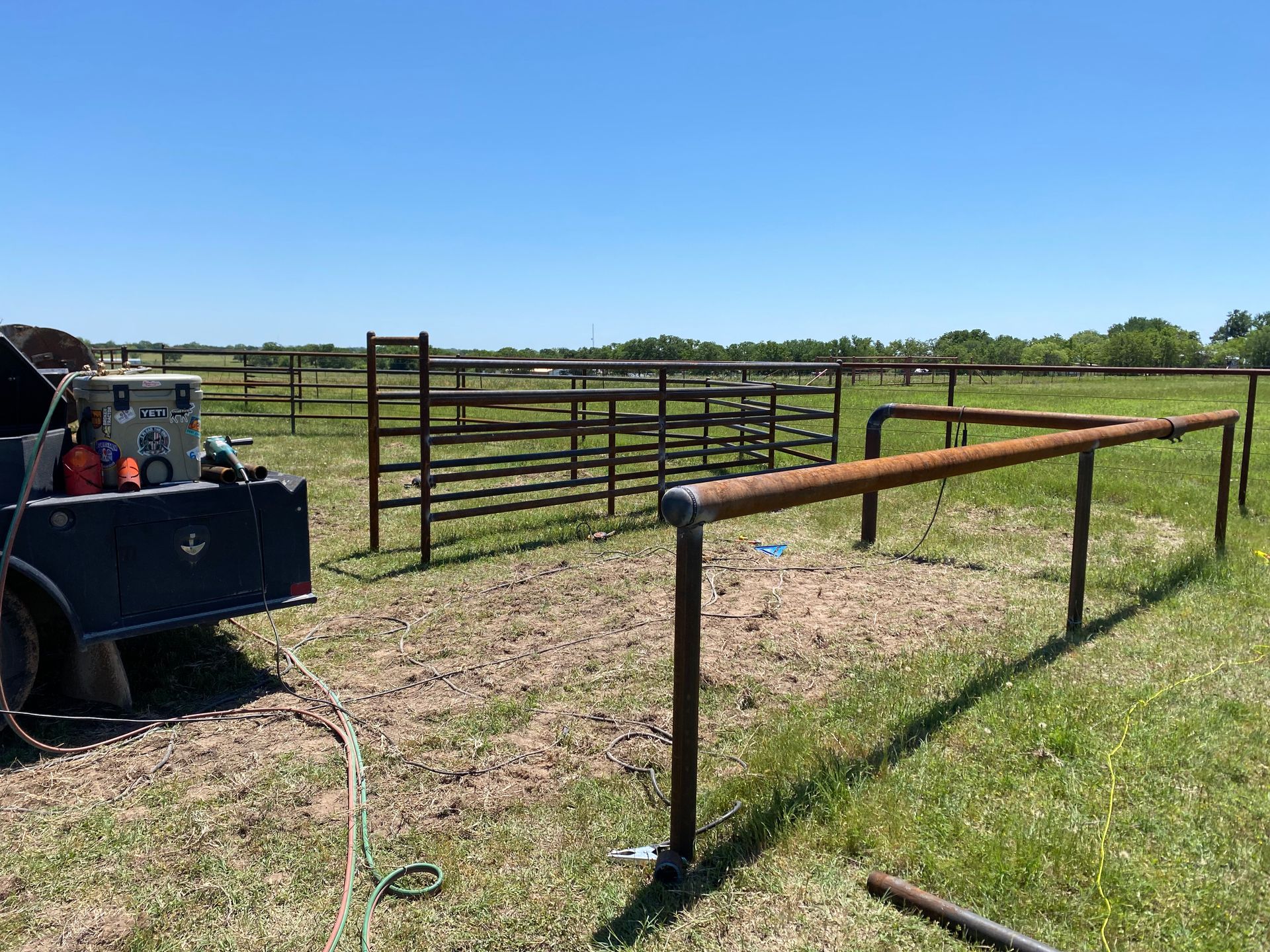 A trailer is parked in a grassy field next to a fence.