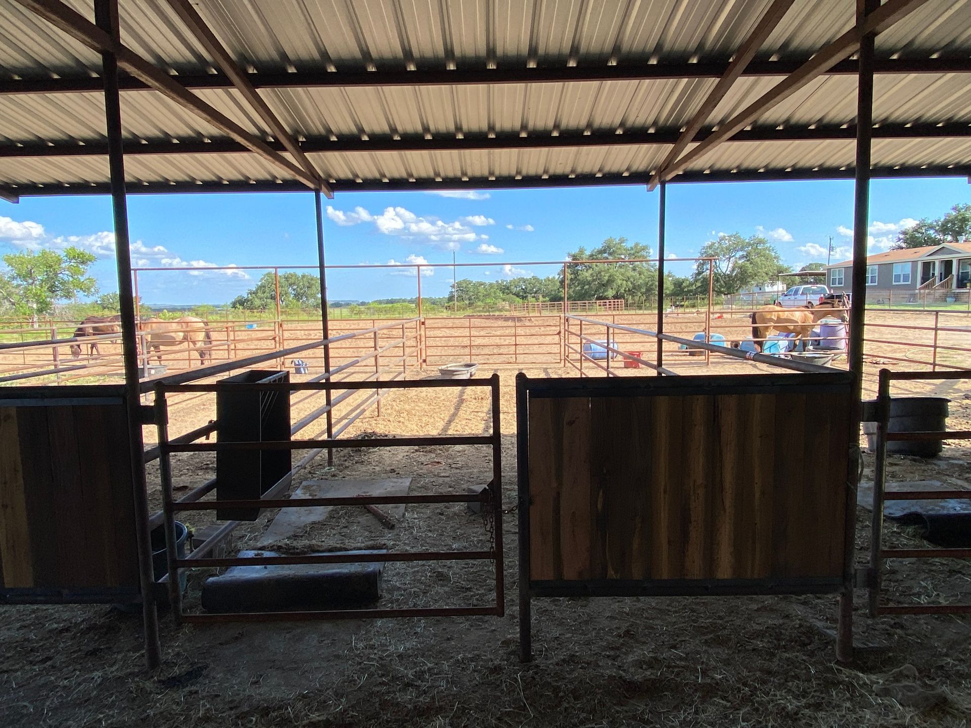 A fenced in area with a roof and a view of a field.