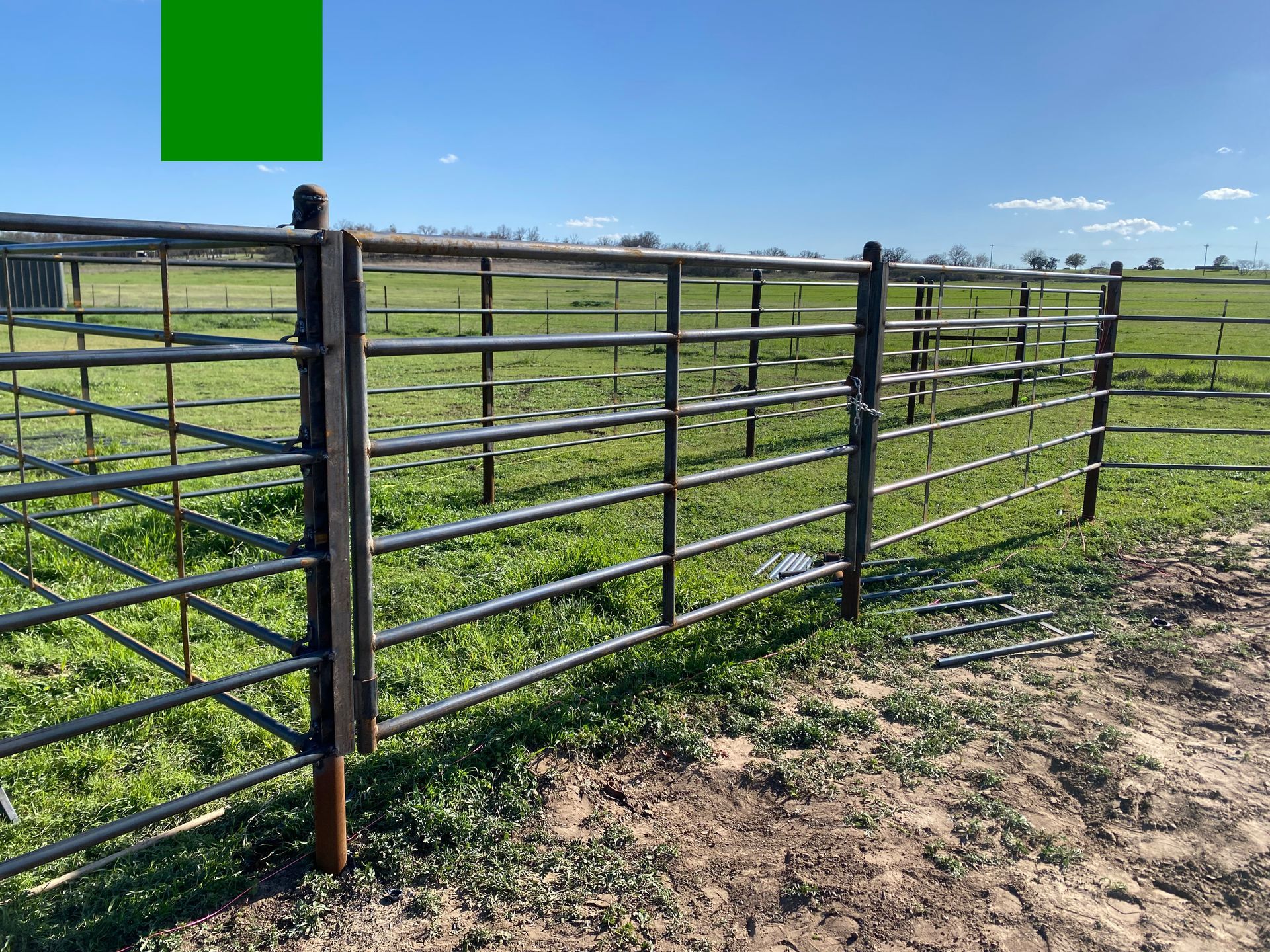 A metal fence is surrounding a grassy field.