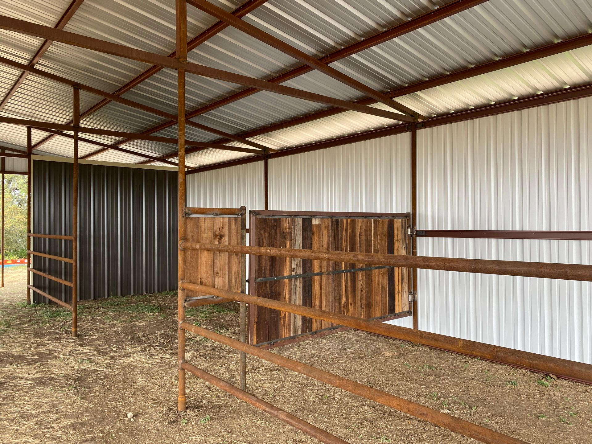 A horse stable with a metal roof and a wooden fence.