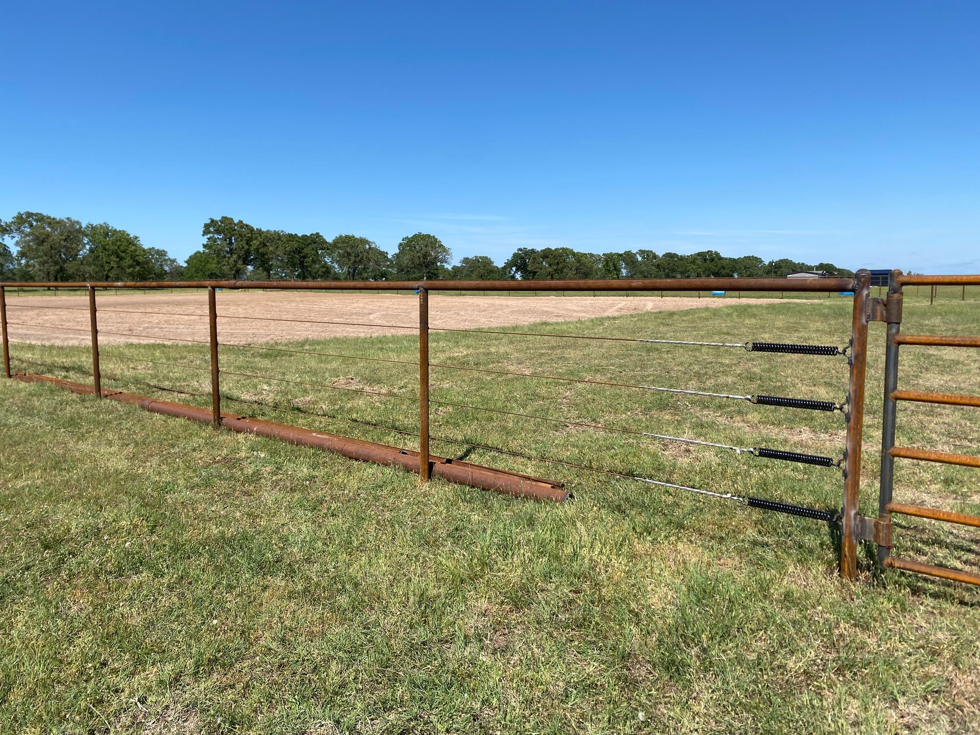 There is a fence in the middle of a grassy field.