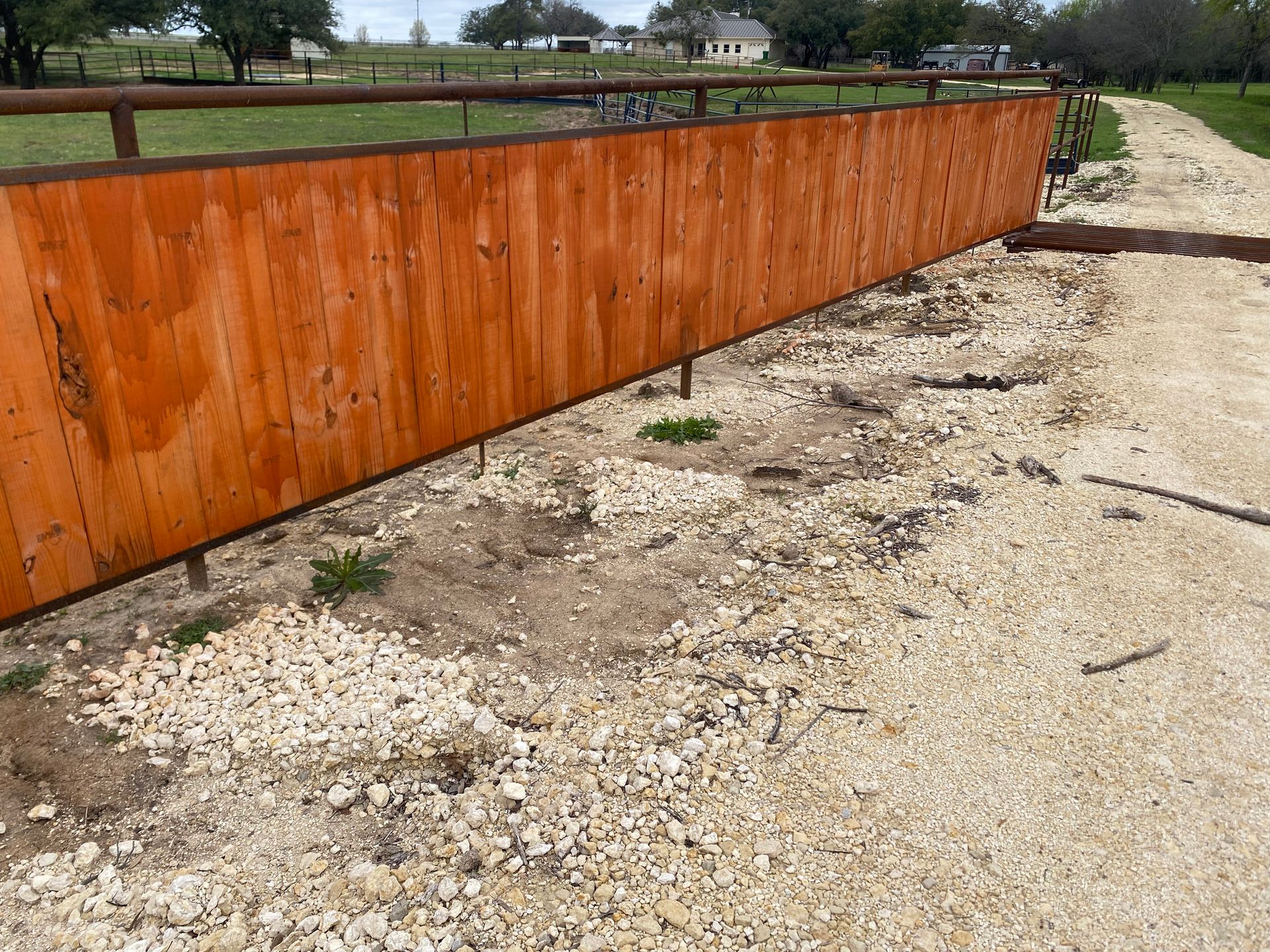 A wooden fence is sitting on top of a gravel road.