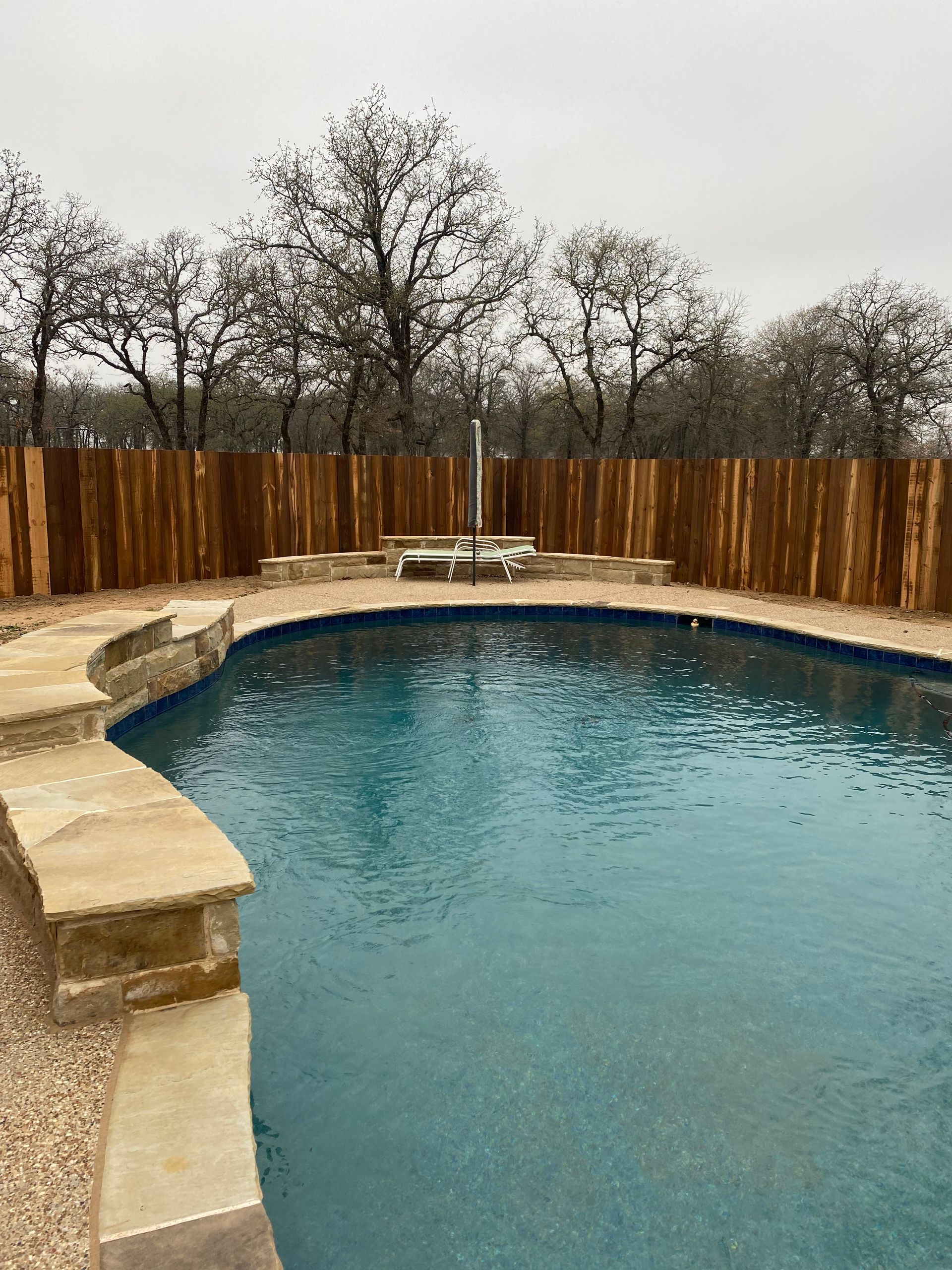 A large swimming pool with a wooden fence around it