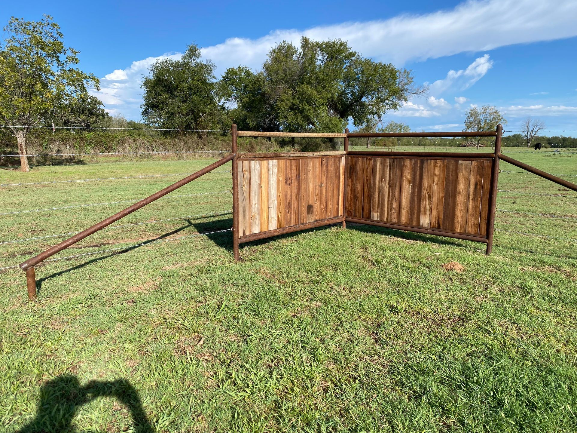 A wooden fence is sitting in the middle of a grassy field.