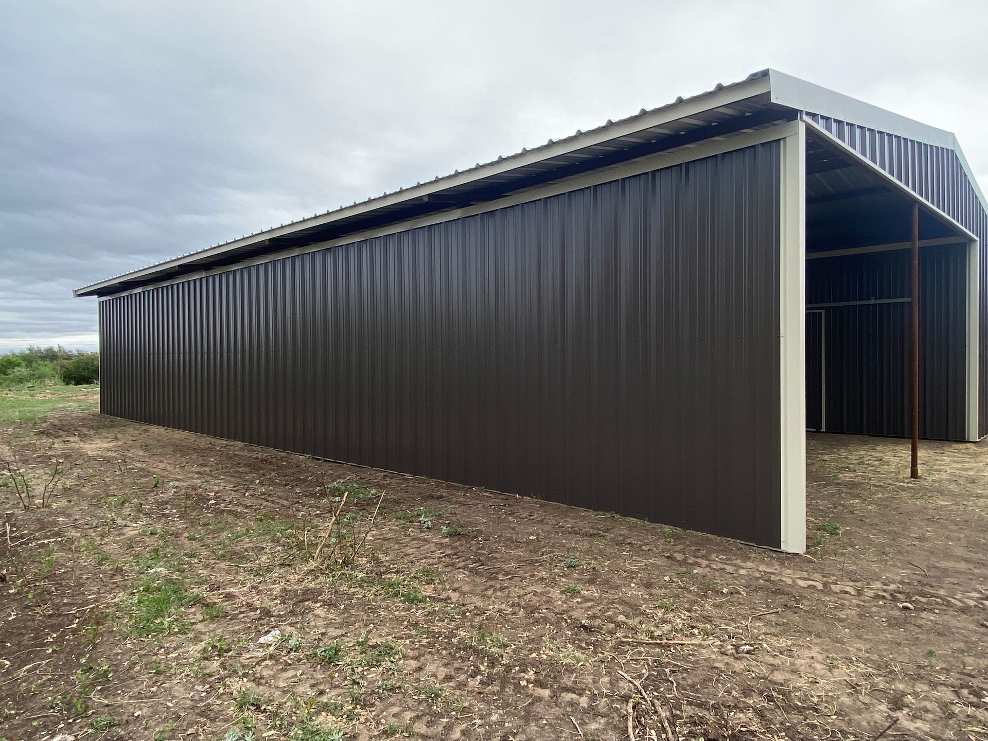 A large metal building is sitting in the middle of a dirt field.