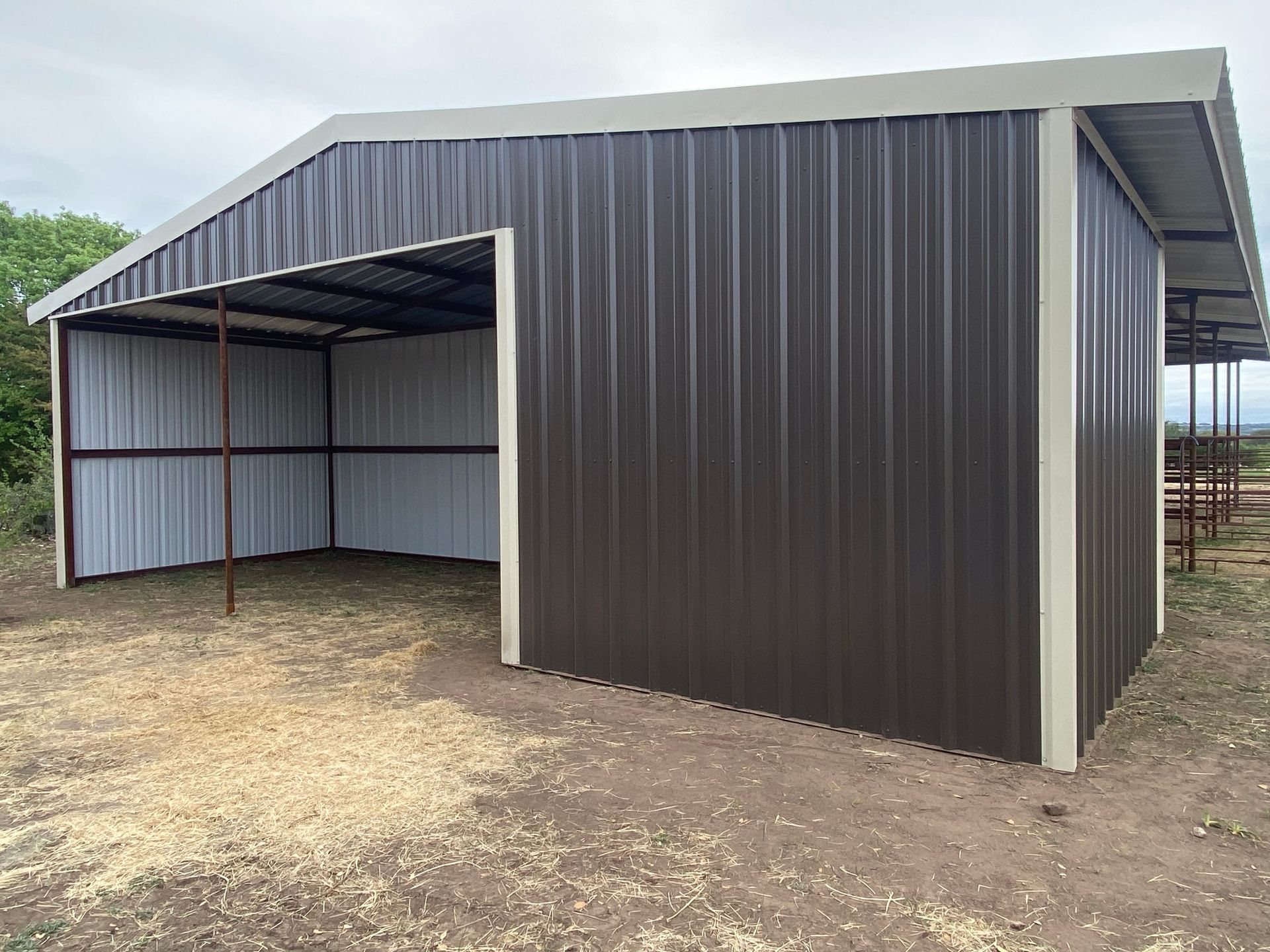 A metal building with a roof is sitting on top of a dirt field.