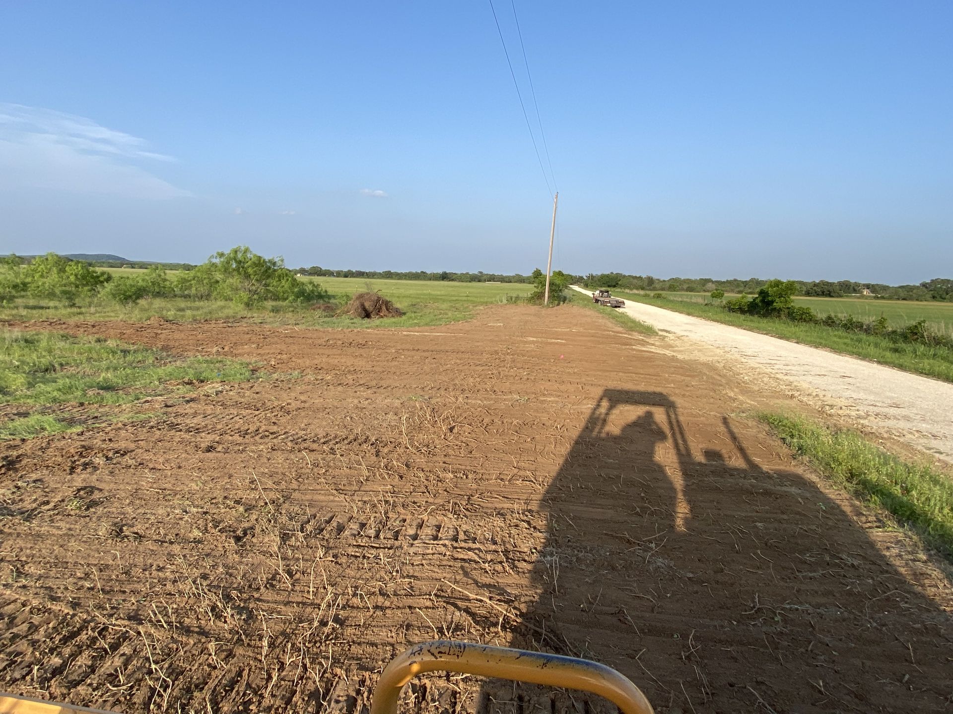 A person is driving a bulldozer down a dirt road.