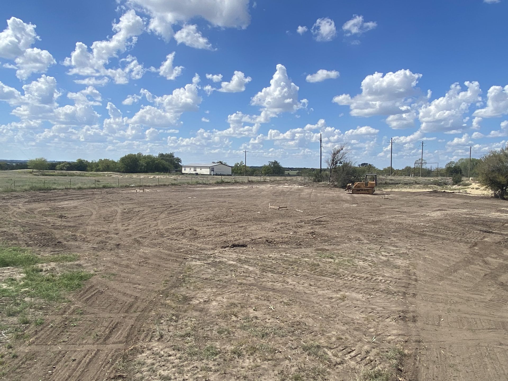 A large dirt field with a blue sky and clouds in the background