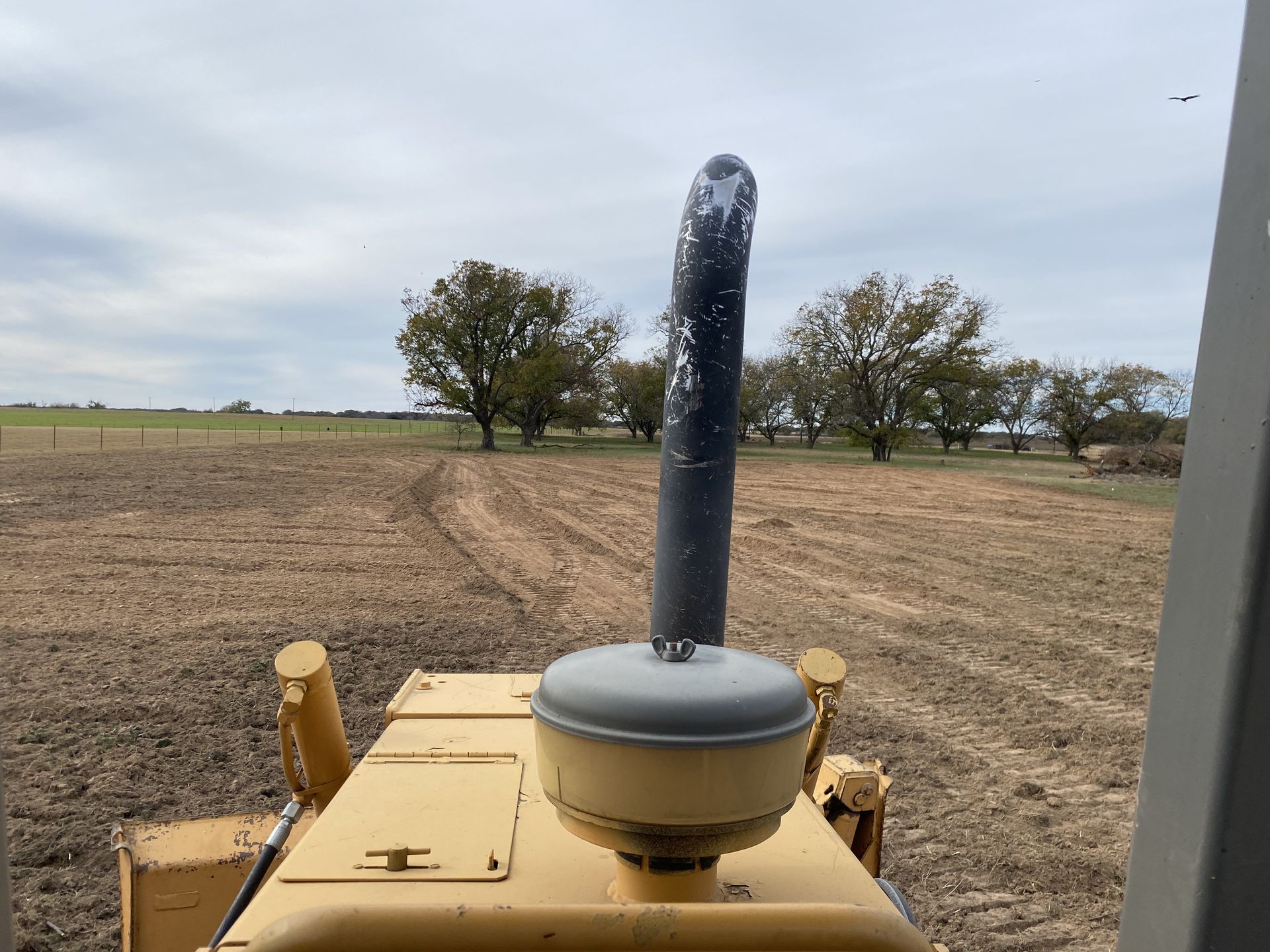 A bulldozer is parked in a field with trees in the background