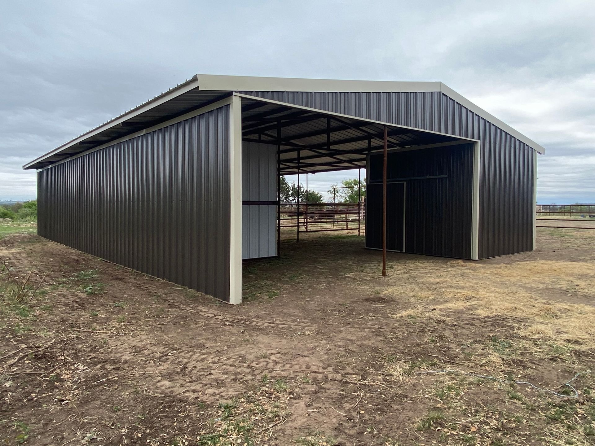 A large metal building is sitting in the middle of a dirt field.