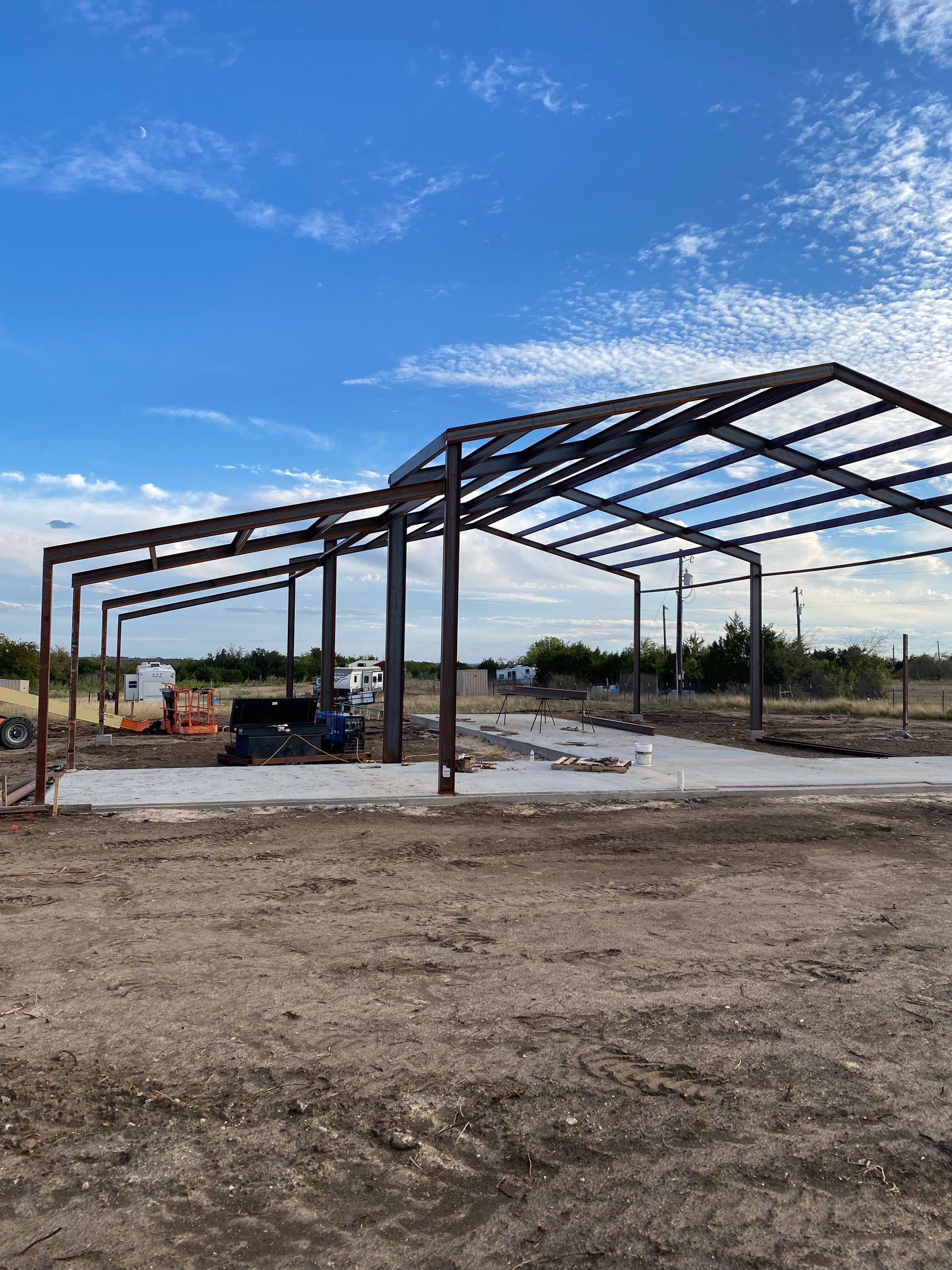 A large metal structure is being built in a dirt field.