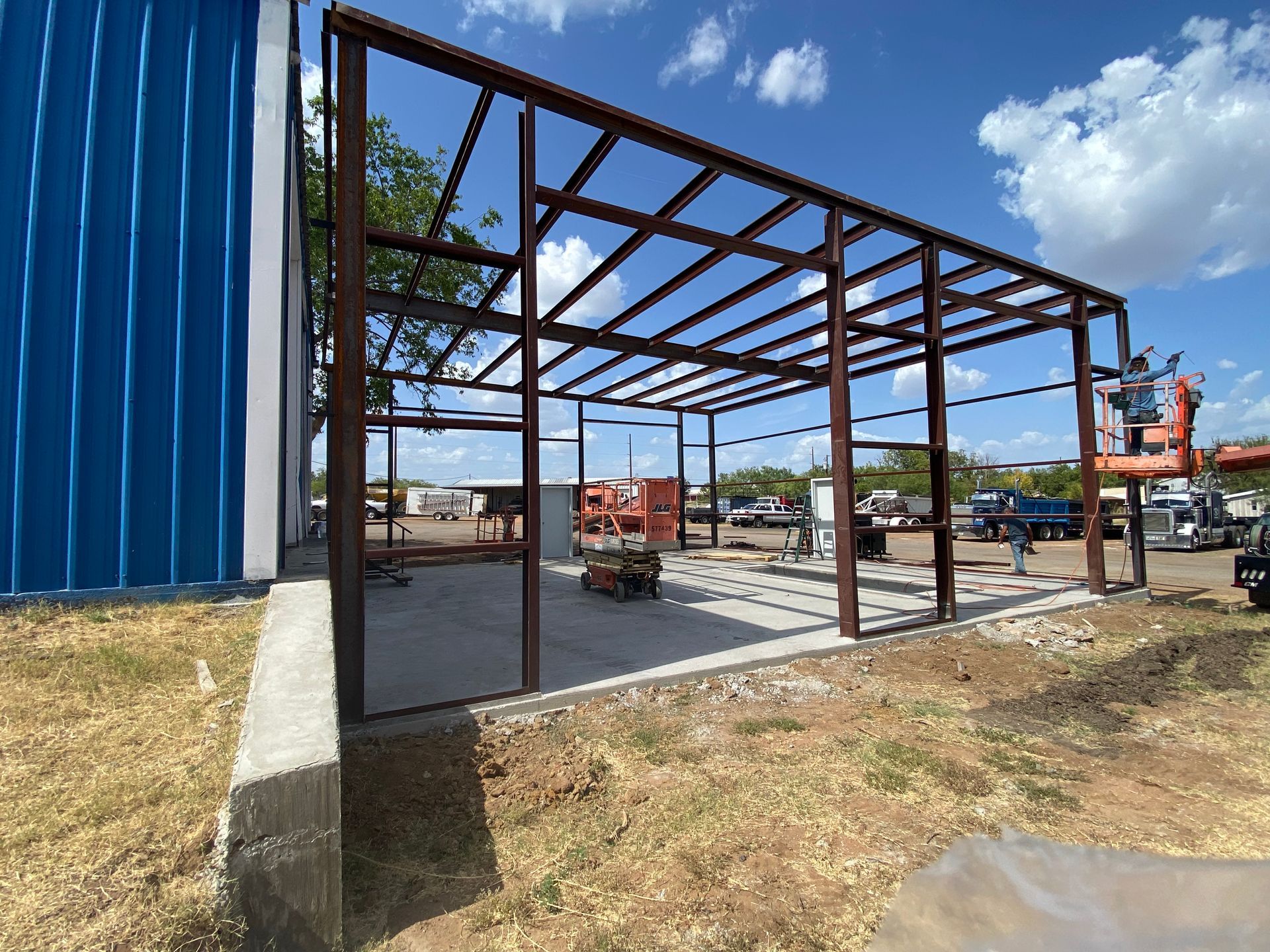 A metal structure is being built next to a blue building.