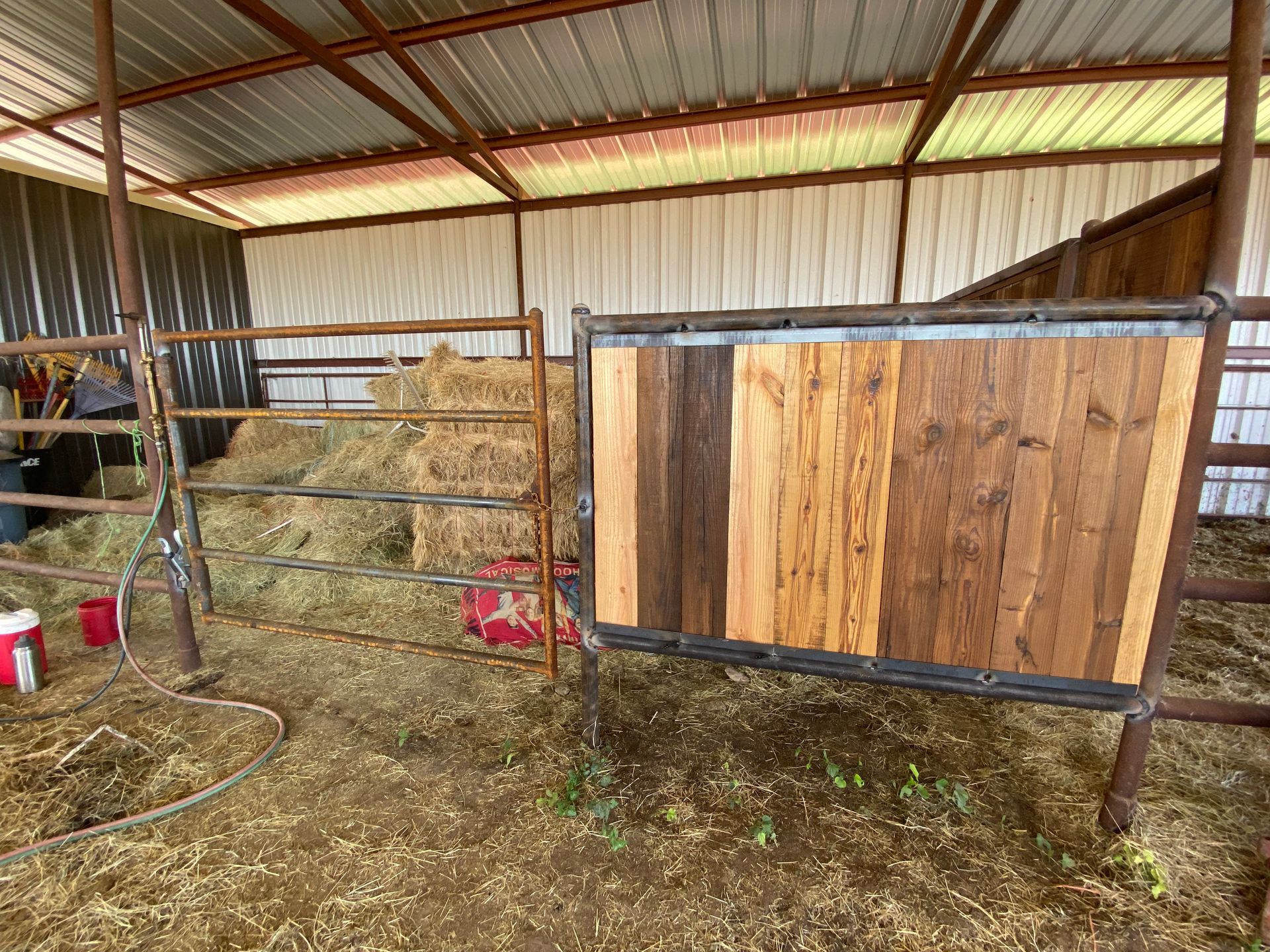 A horse stable with hay and a wooden fence.