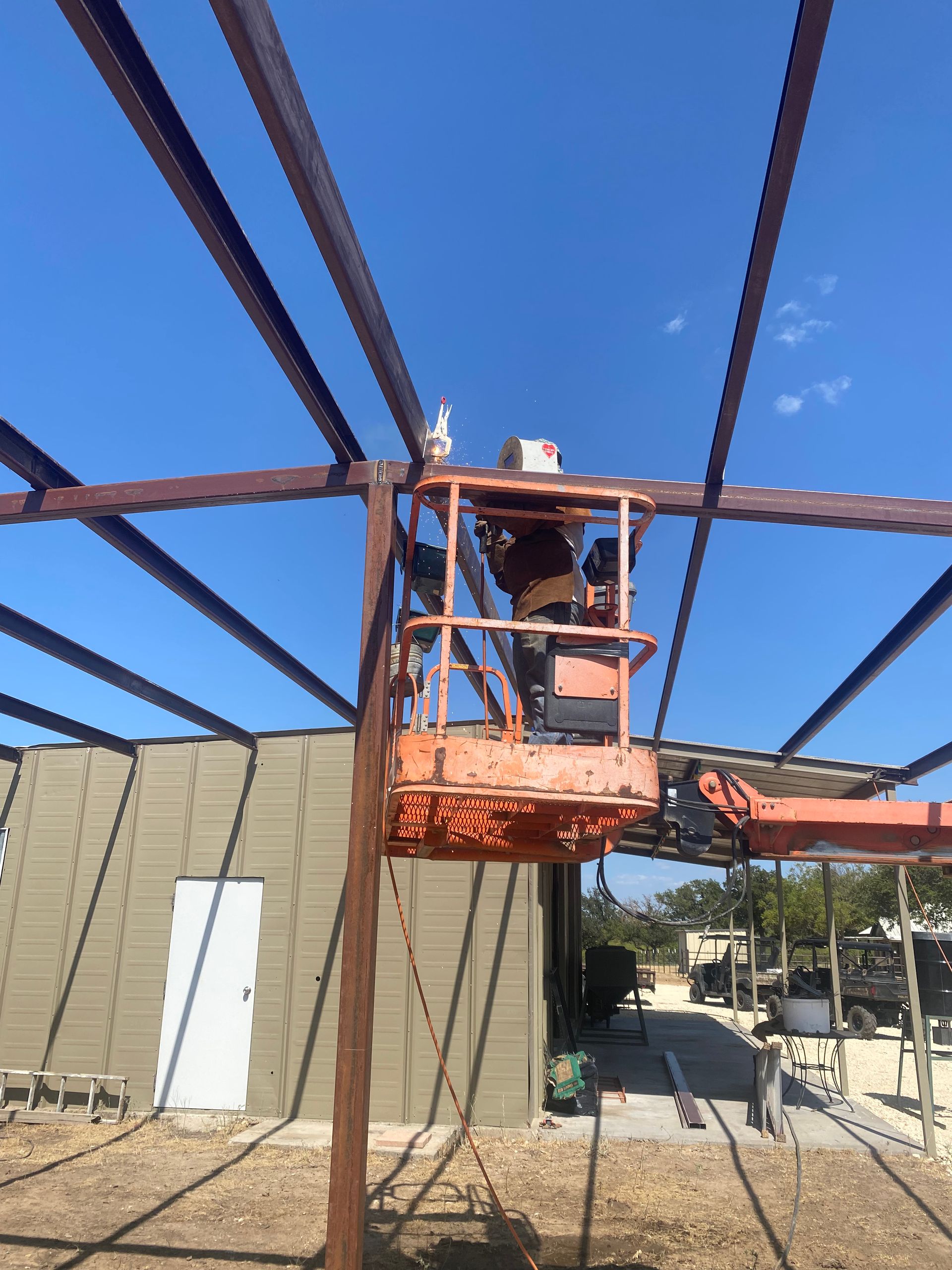 A man is standing on a lift working on a metal structure.