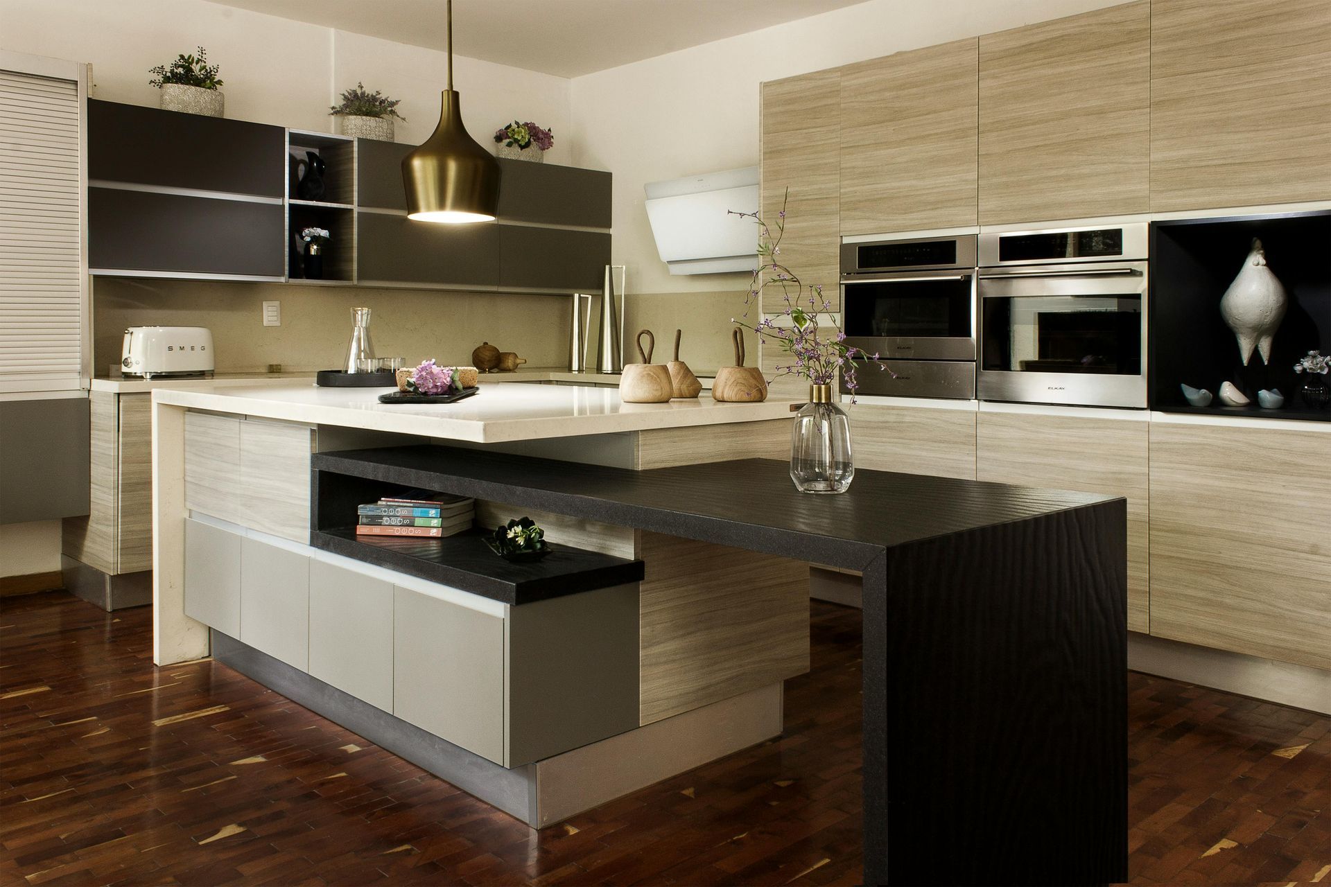 Modern kitchen with island, gray and wood cabinets, stainless steel appliances, and dark countertops.