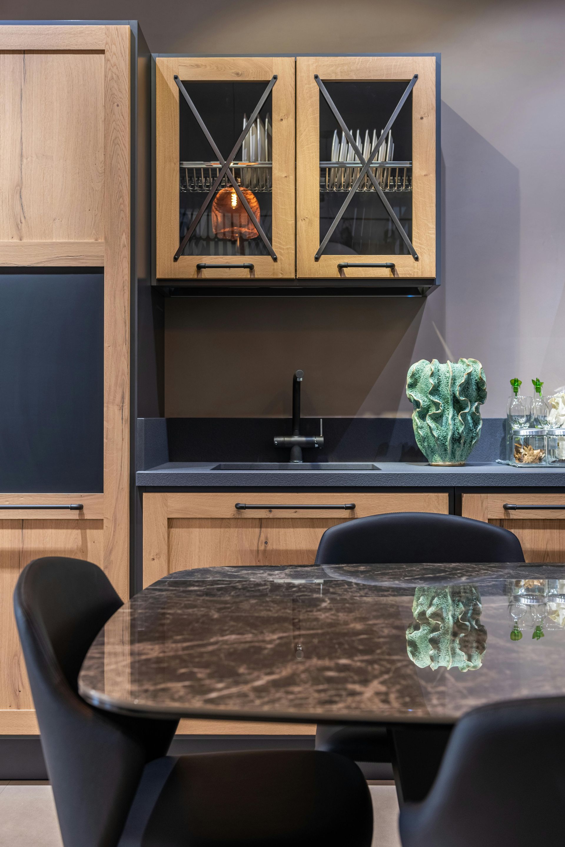 Kitchen with wooden cabinets, dark countertops, and a dining table with chairs.