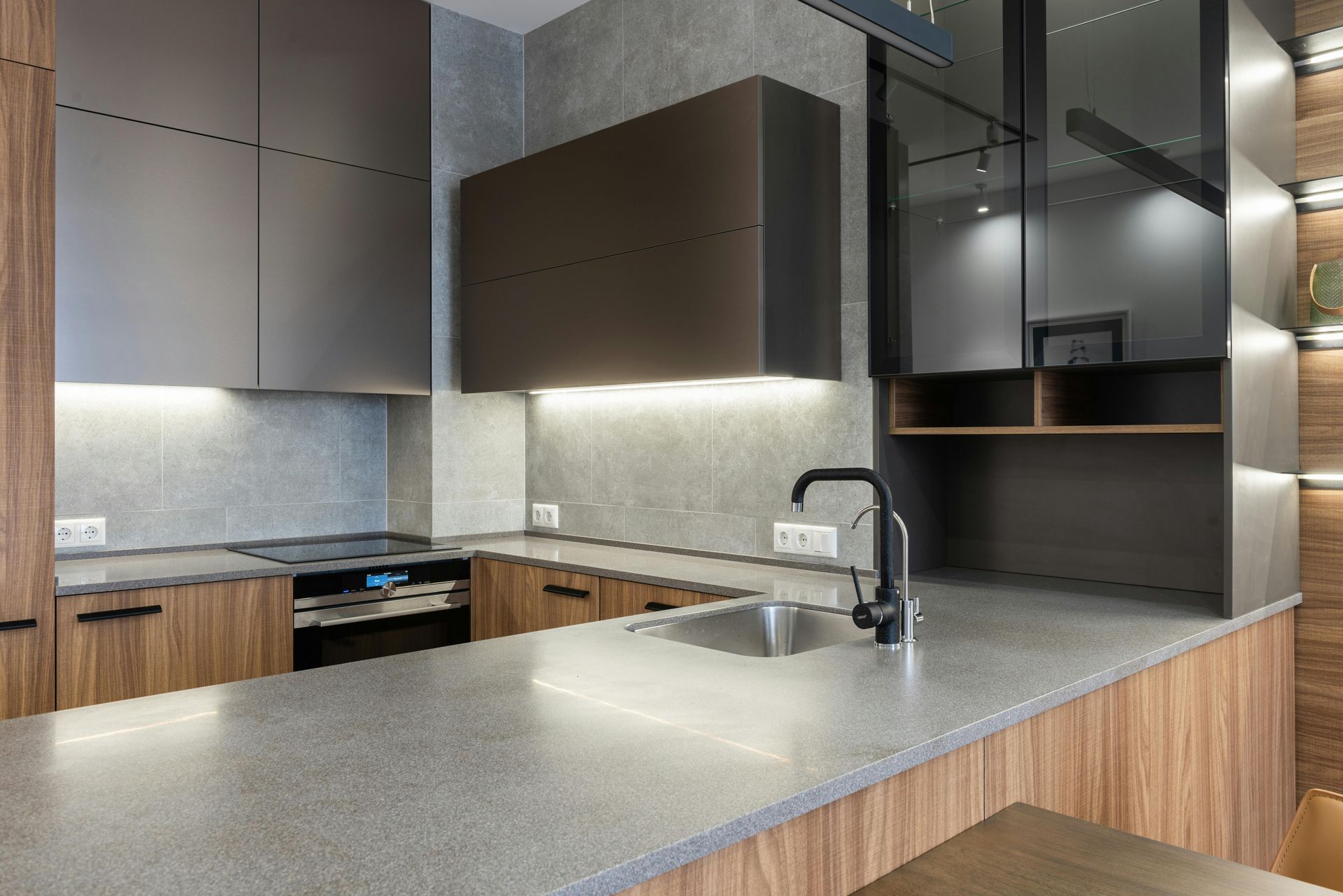 Modern kitchen with gray countertops, wood cabinets, and stainless steel sink.