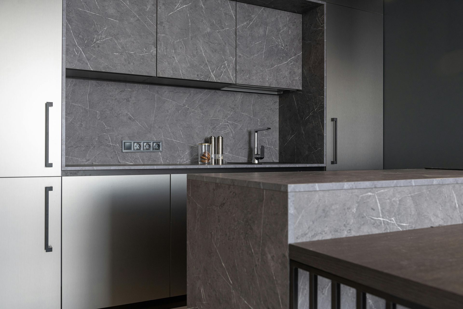Modern kitchen with gray marble-look cabinets and countertop. White lower cabinets and dark handles.