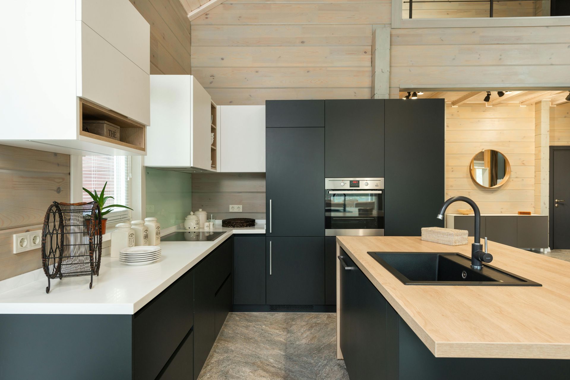 Modern kitchen with white and dark gray cabinets, island with sink, and wooden countertops.