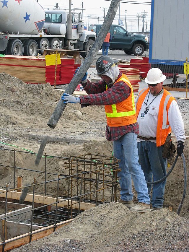Concrete workers pouring a concrete foundation into a mold