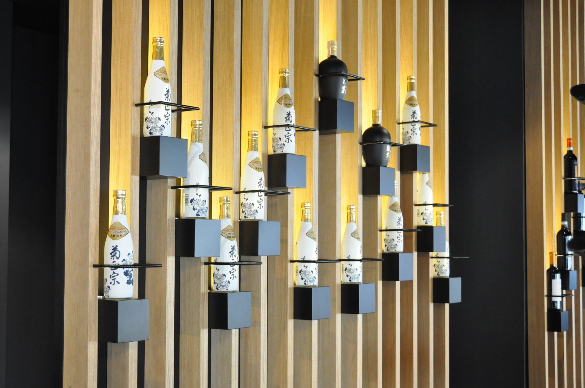 Una fila di bottiglie è appesa a una parete di legno.