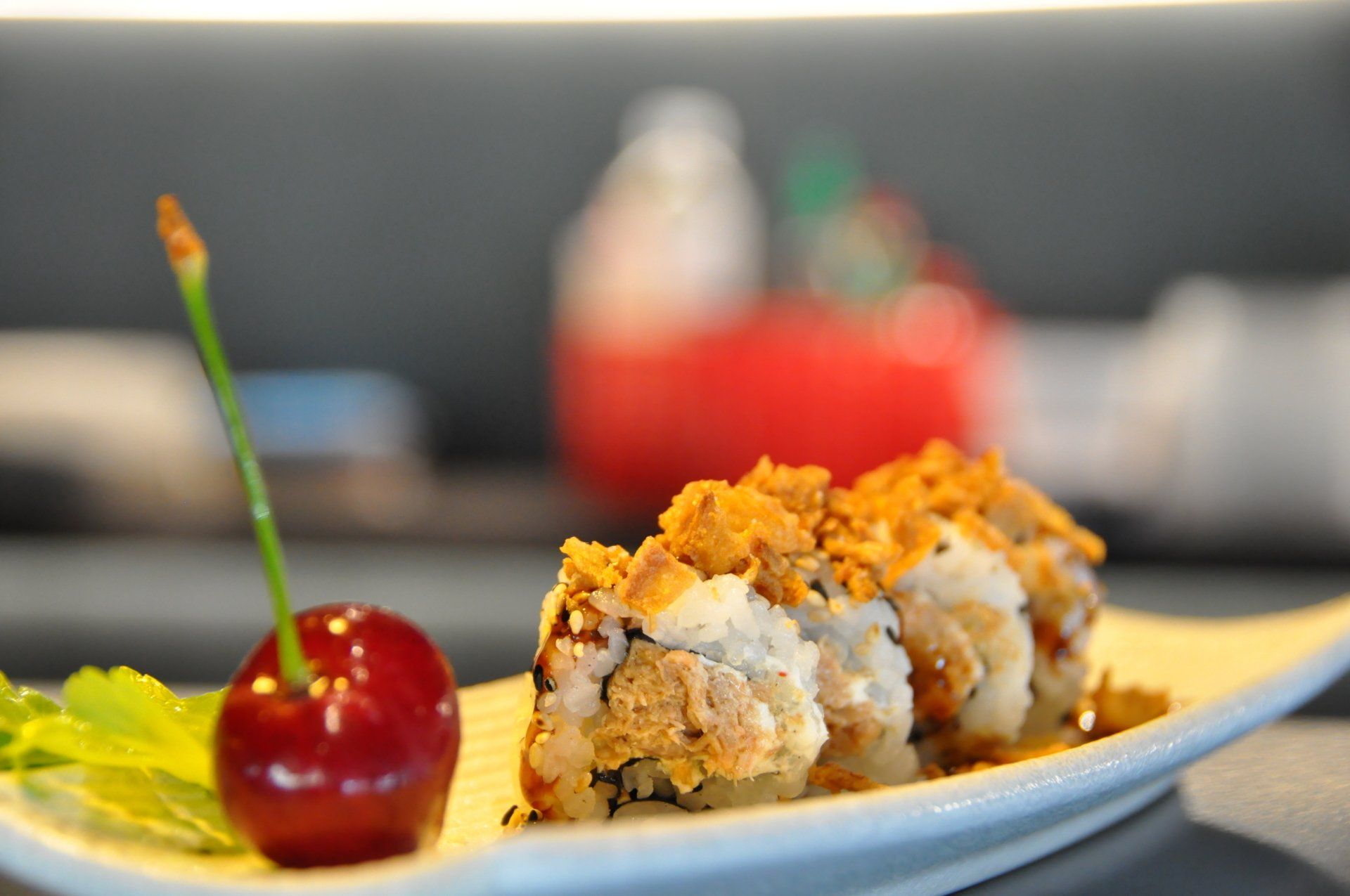 Un rotolo di sushi con sopra una ciliegia su un piatto.