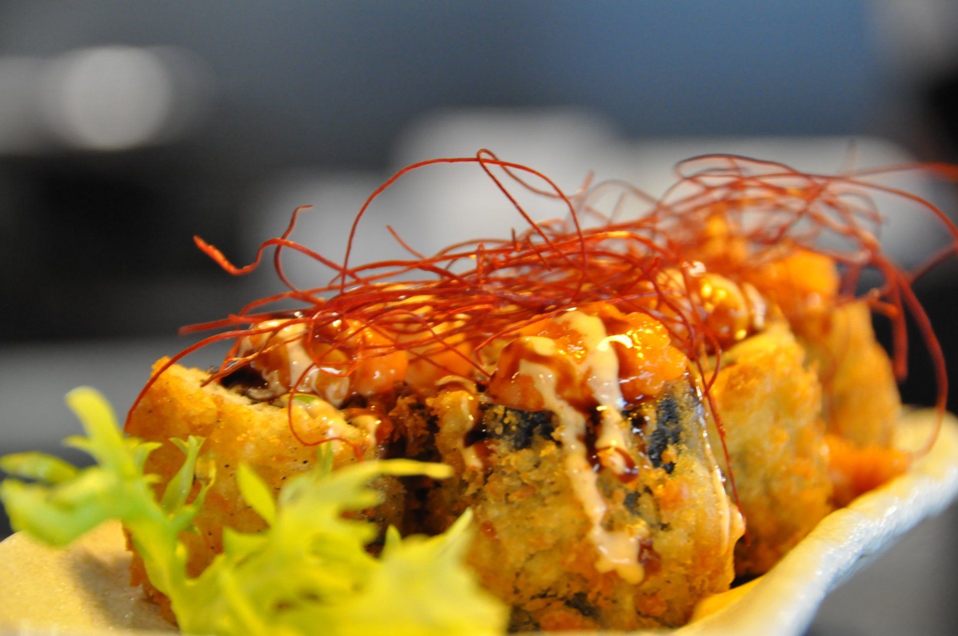 Un primo piano di un rotolo di sushi su un piatto con salsa rossa.