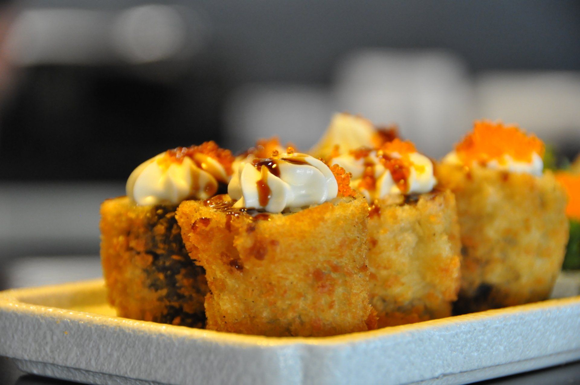 Un primo piano di rotoli di sushi fritti su un piatto bianco.