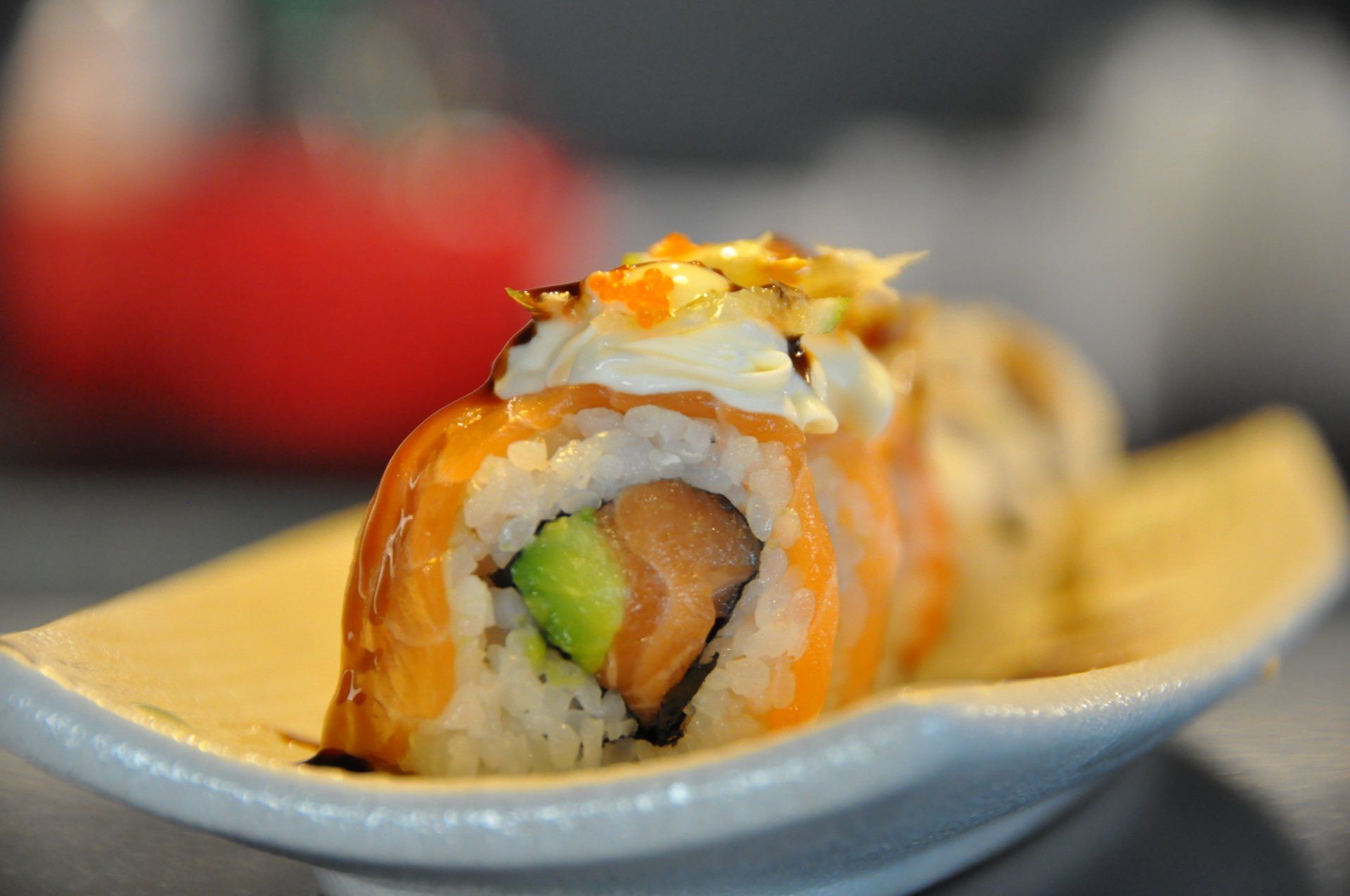 Un primo piano di un rotolo di sushi su un piatto bianco.