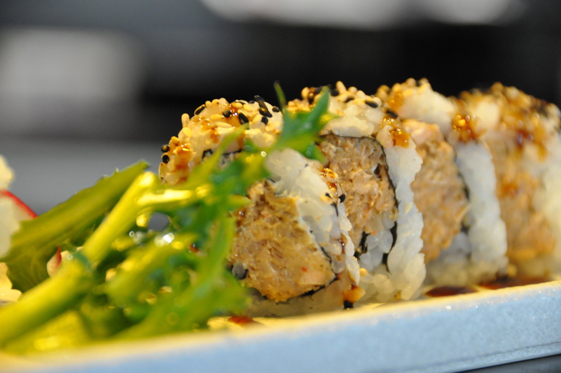 Un primo piano di un rotolo di sushi su un piatto con verdure.