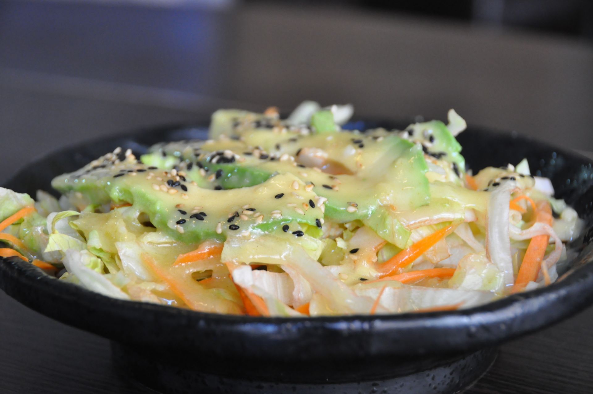 Un primo piano di un'insalata in una ciotola nera su un tavolo.