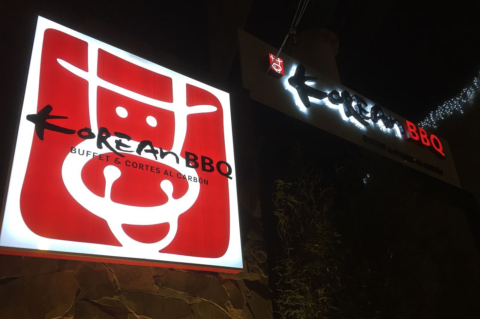 Letreros de restaurante de barbacoa coreana, rojos y blancos, iluminados por la noche.
