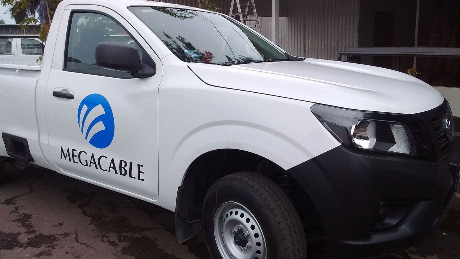 Camioneta Megacable blanca con logo azul.