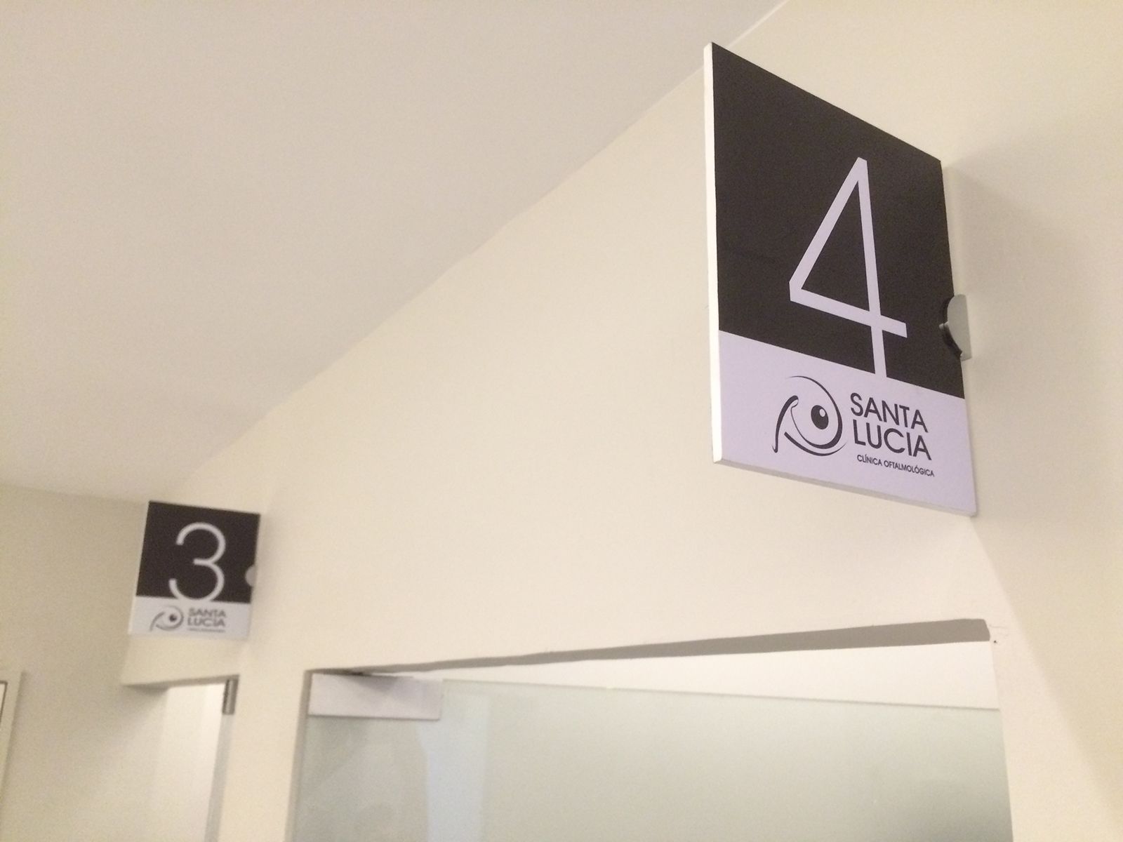 Habitaciones números 3 y 4 con carteles en blanco y negro, en un edificio con pared blanca.