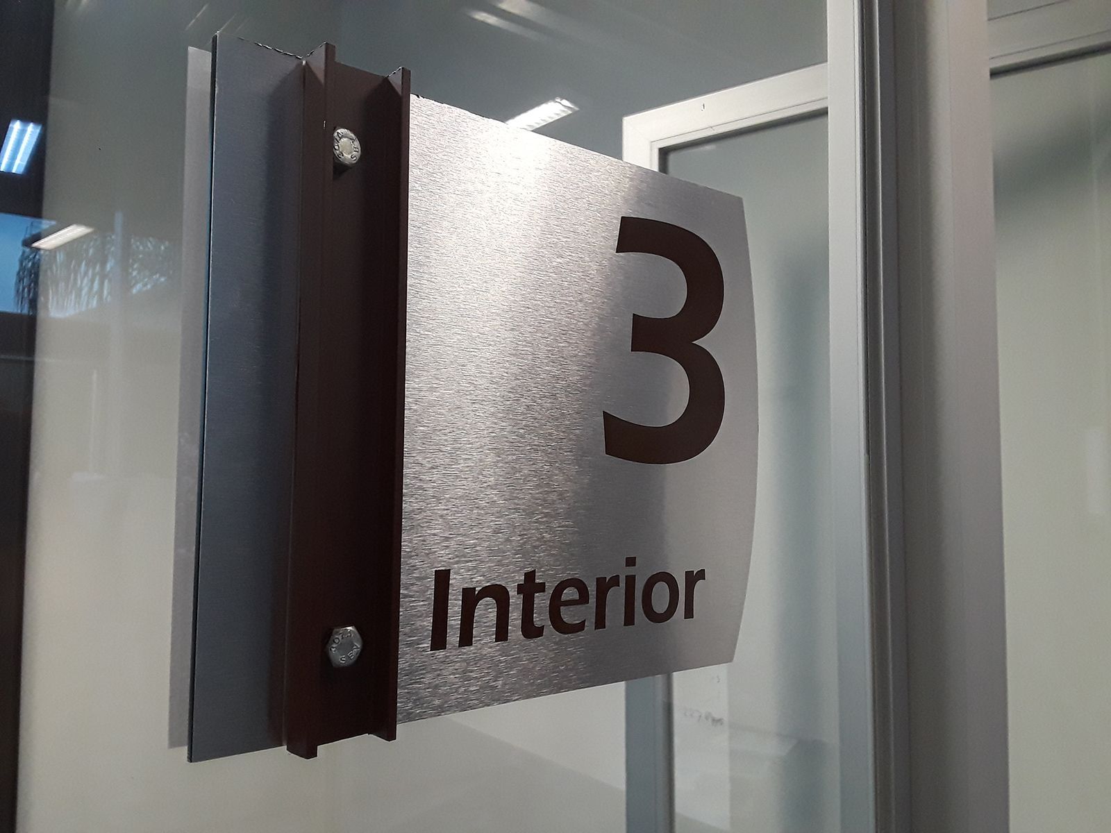 Número de habitación: Placa plateada con detalles marrones.