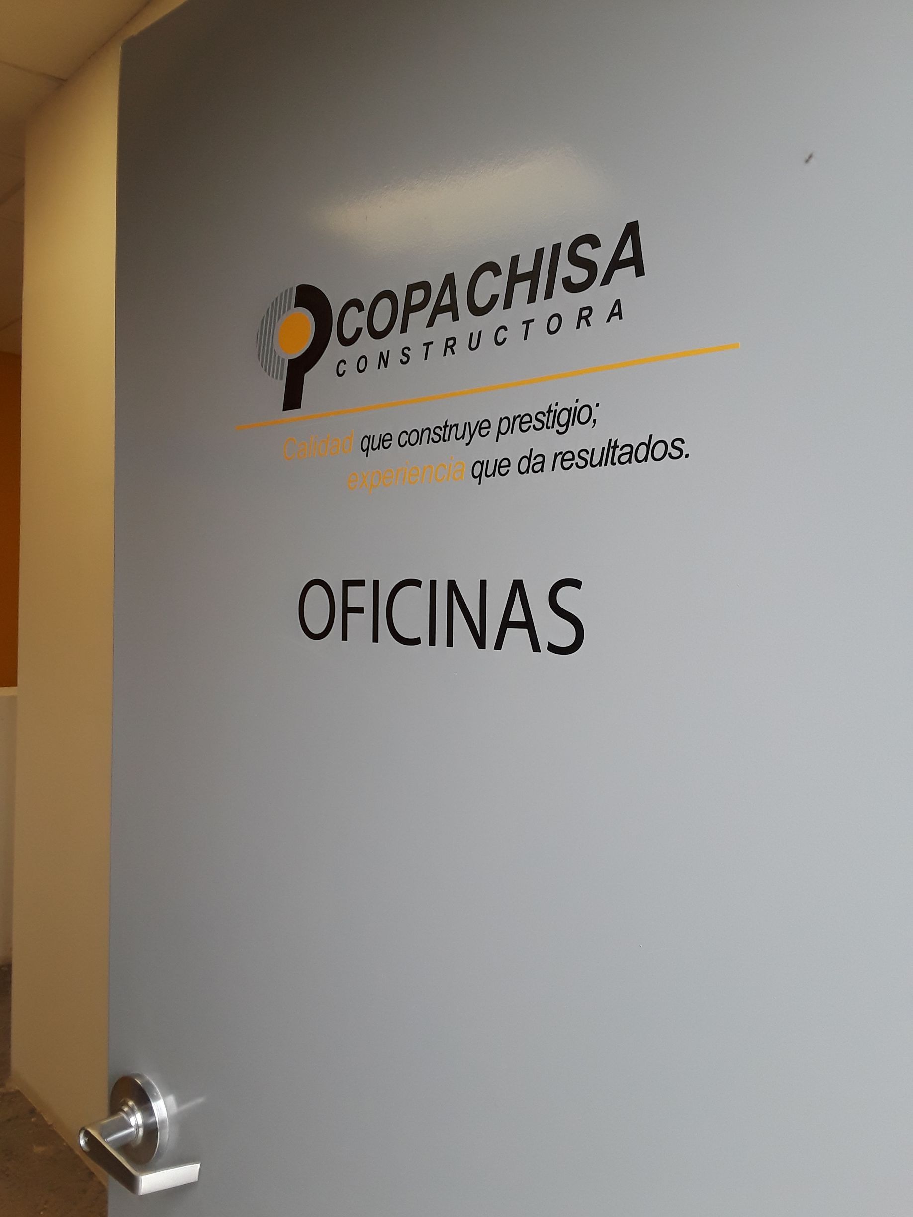 Puerta de oficina color gris con logo “COPACHISA CONSTRUCTORA” y texto “OFICINAS”.