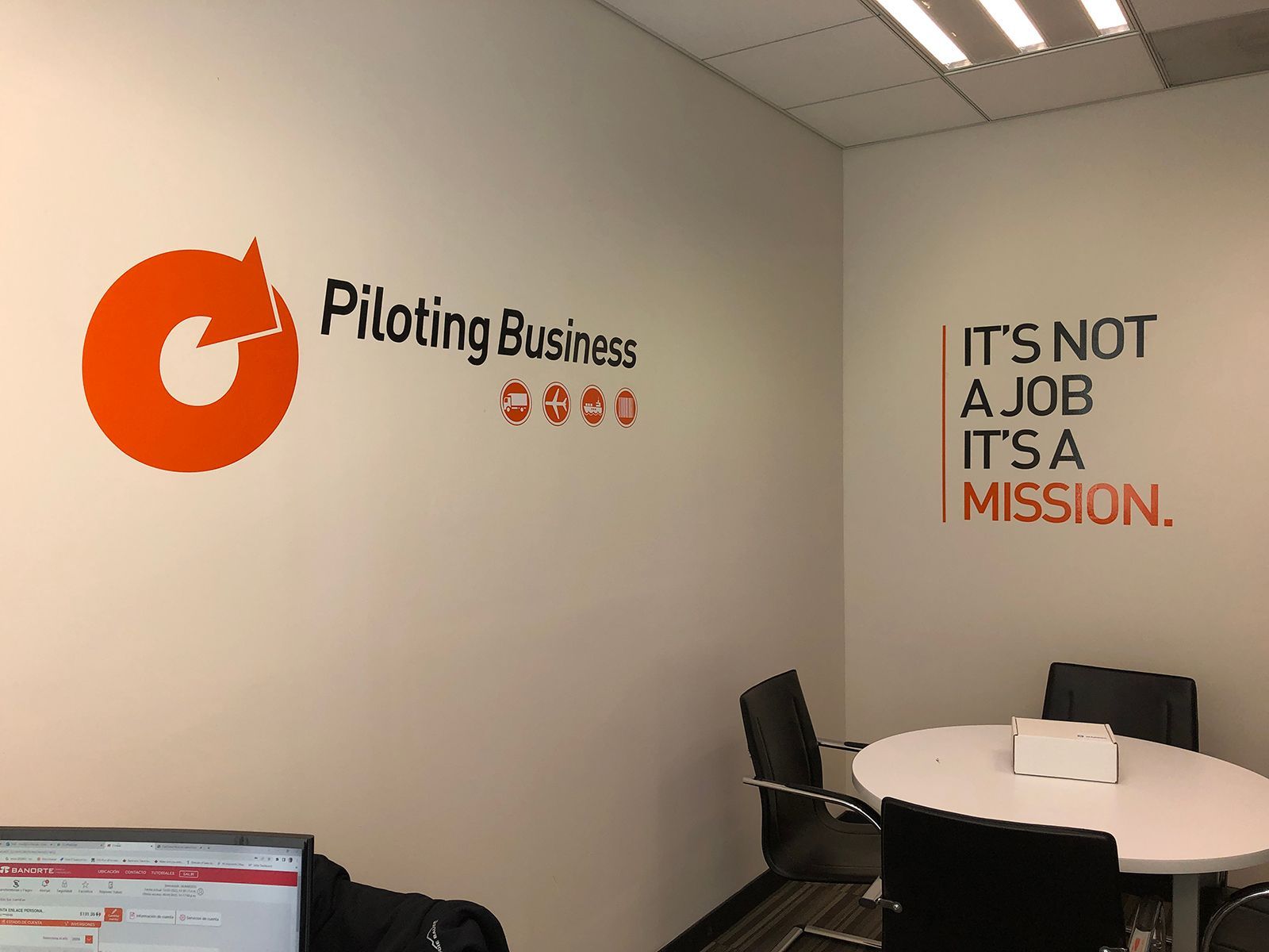 Rincón de oficina con vinilos decorativos motivacionales y una mesa redonda rodeada de sillas.