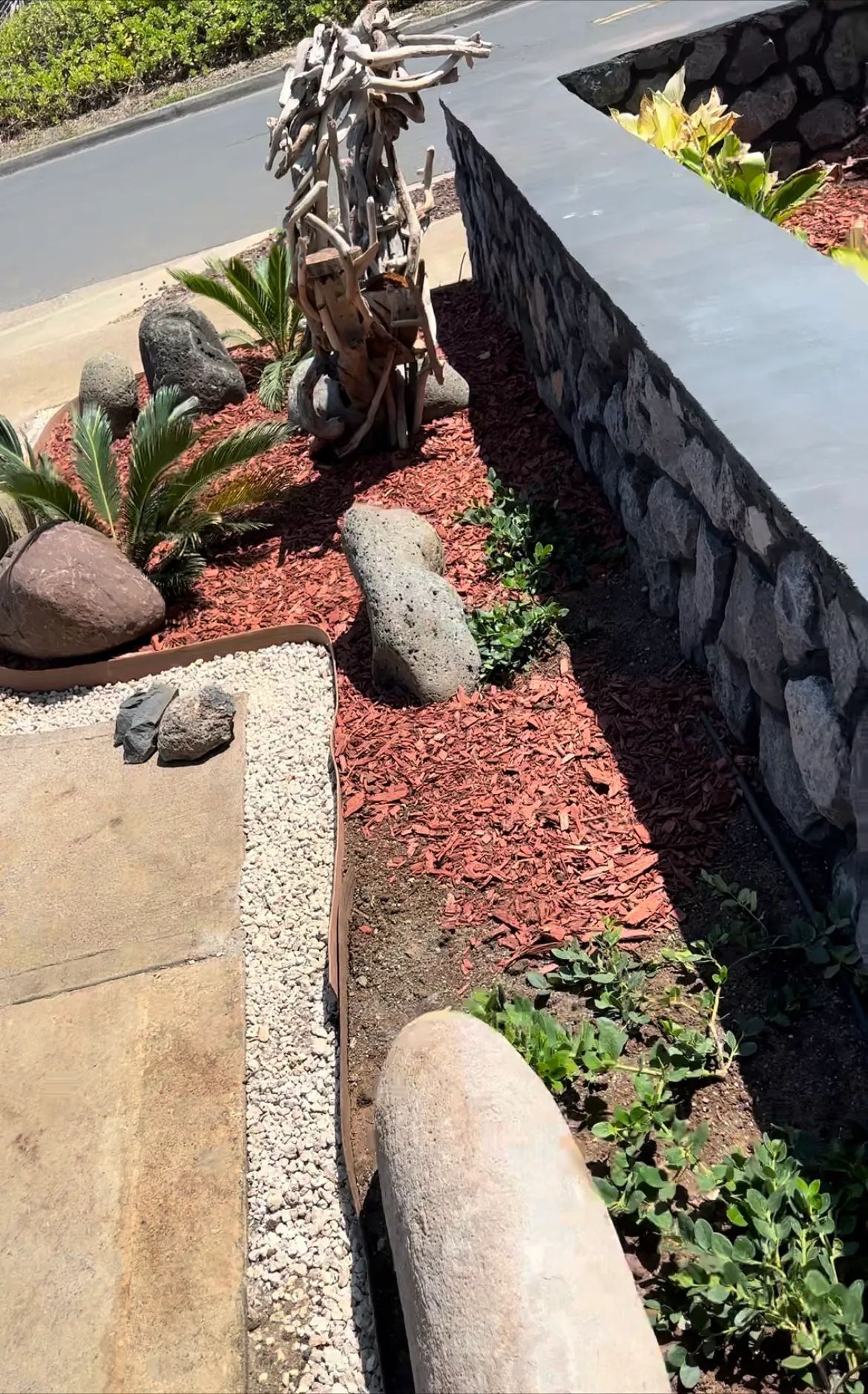 A stone wall is surrounded by rocks and plants in a garden.