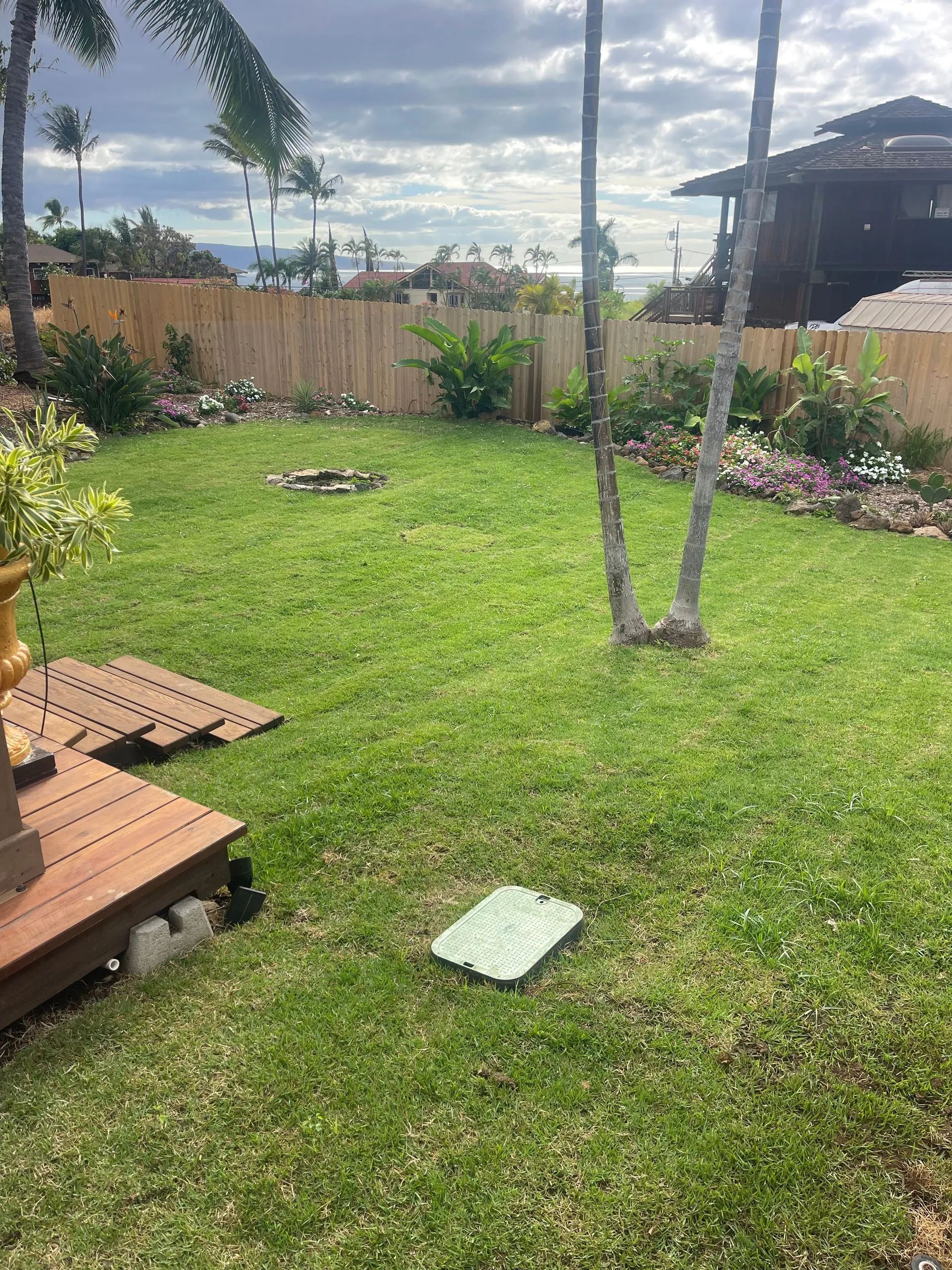 A large lush green lawn with a wooden deck in the middle of it.