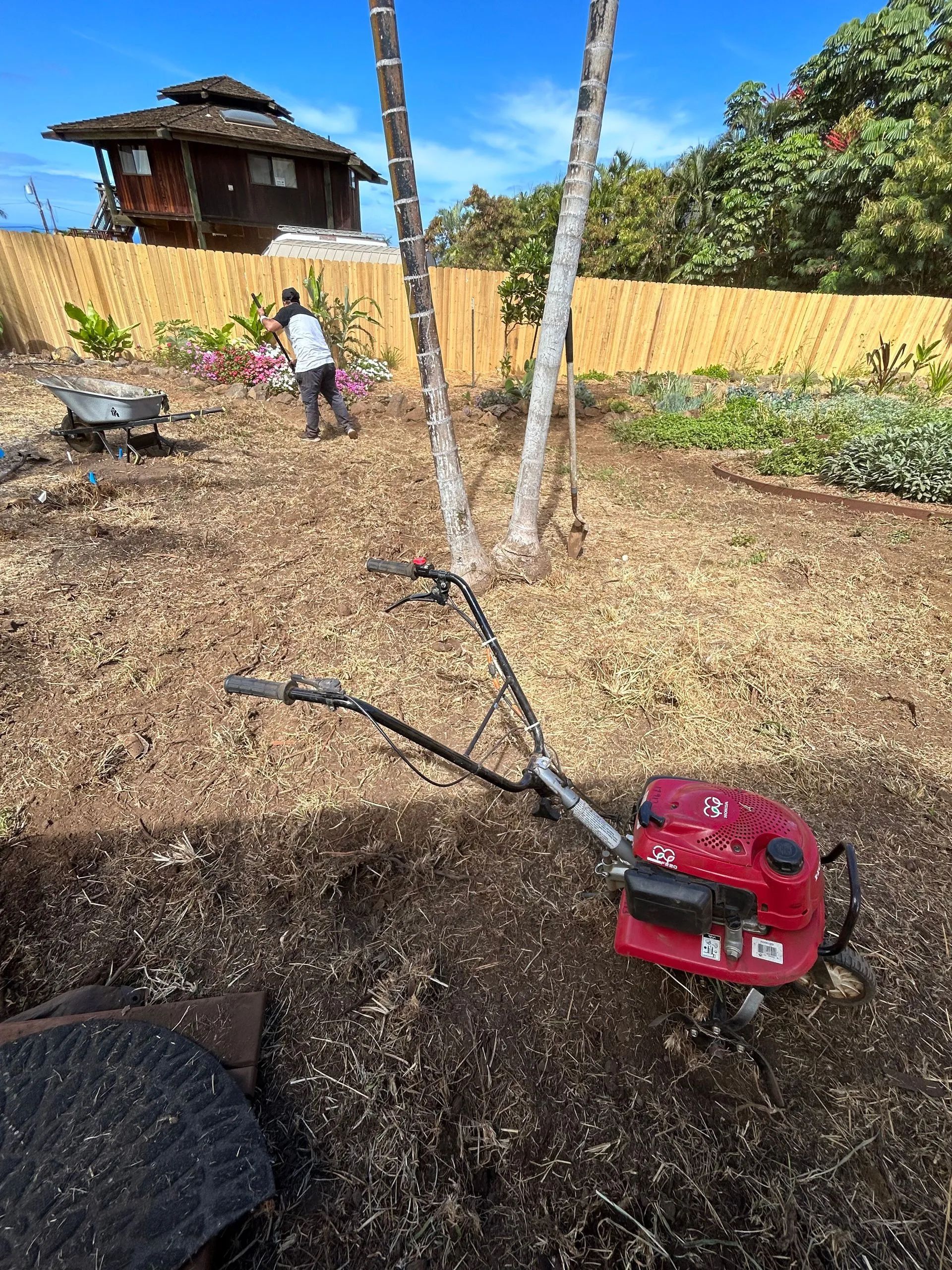 A red lawn mower is sitting in the middle of a dirt field.