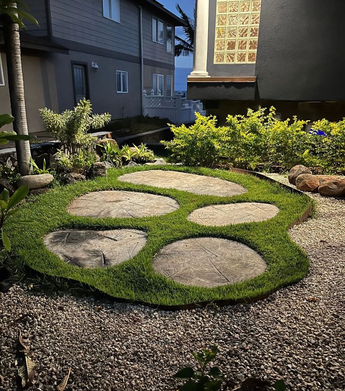 A stone walkway in the shape of a paw print in a garden.