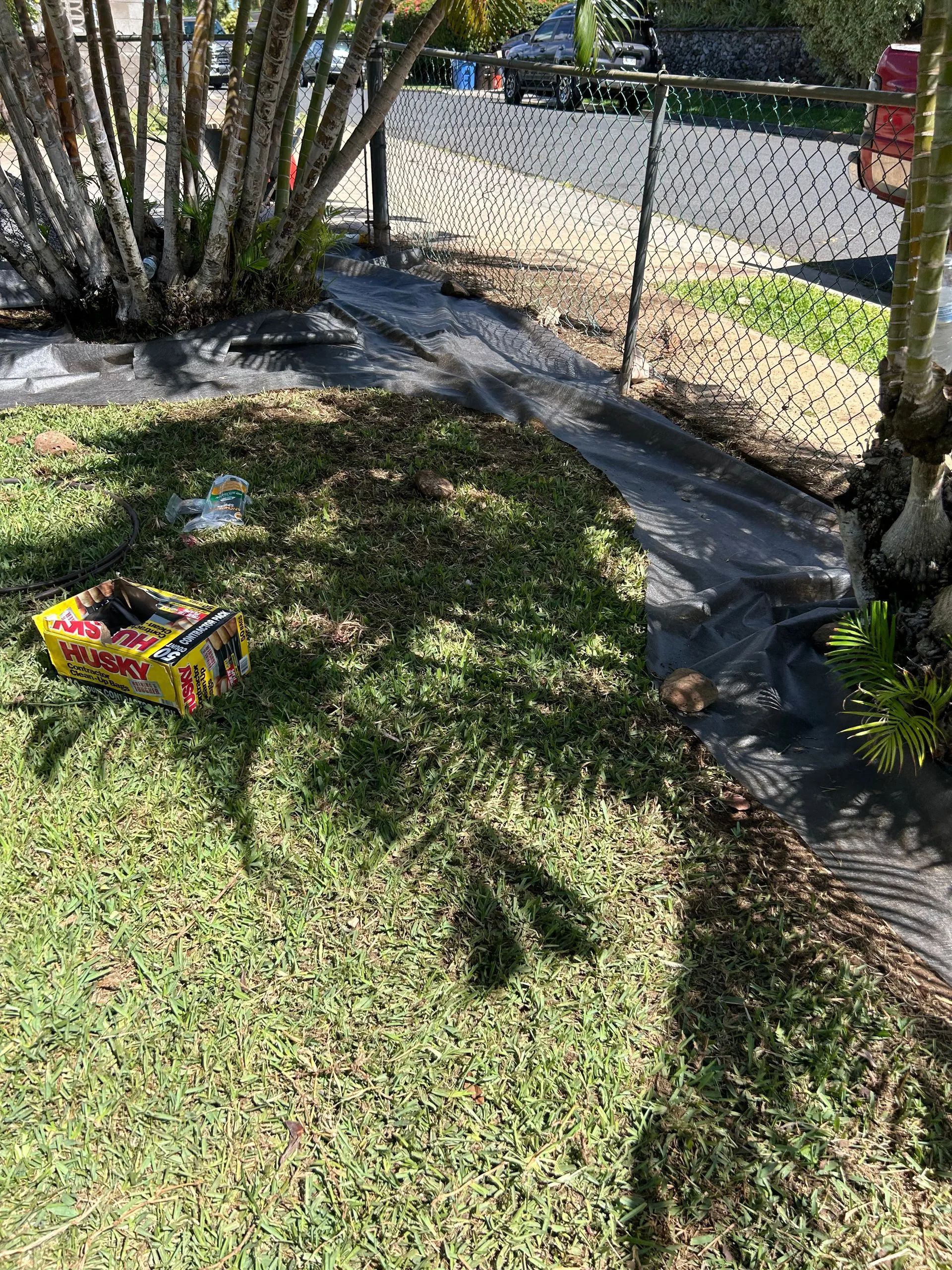 A yellow box is sitting on top of a lush green lawn next to a fence.